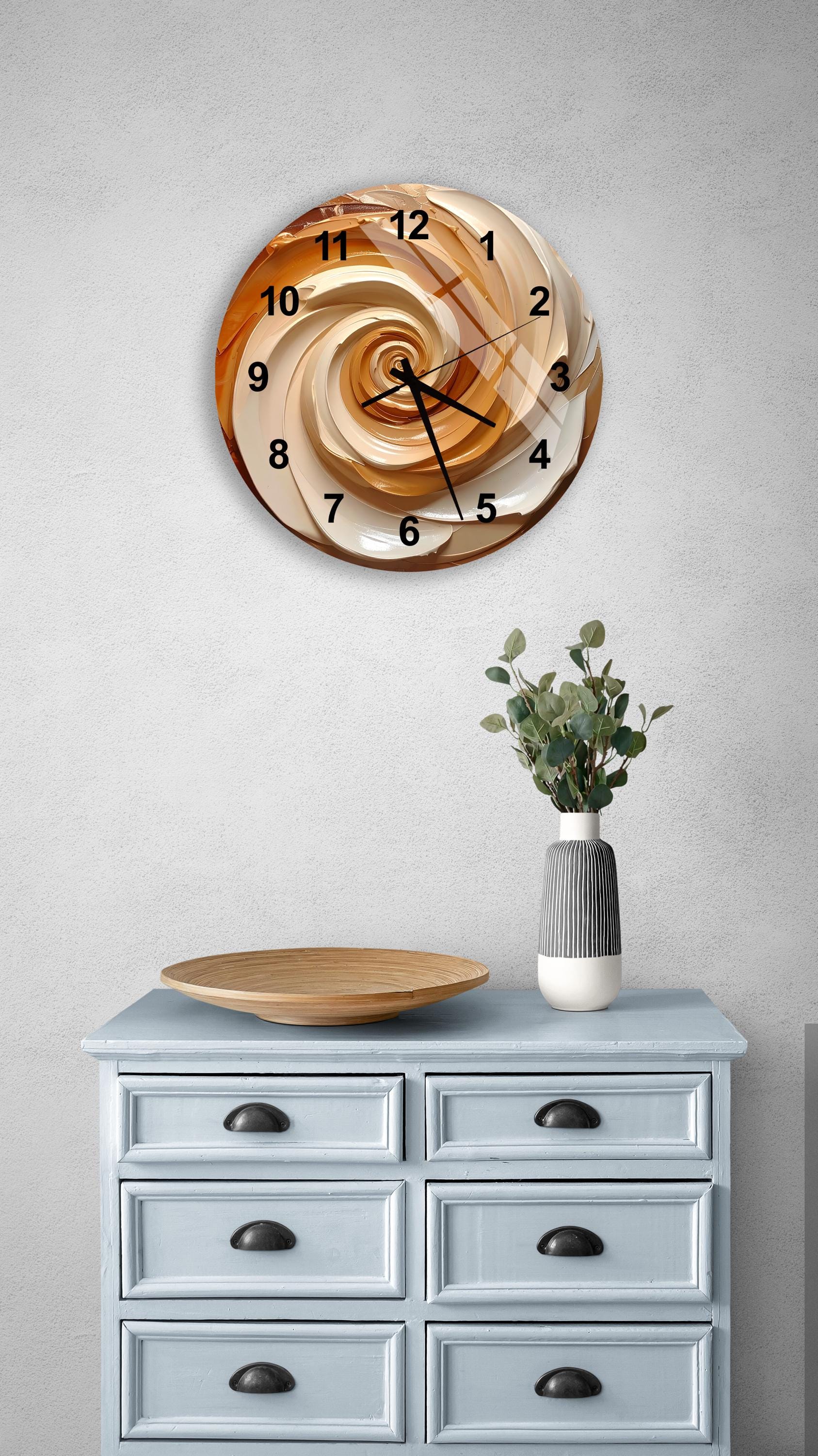 a wall clock with a spiral design, a wooden tray, a vase with greenery, and a light blue dresser with six drawers.