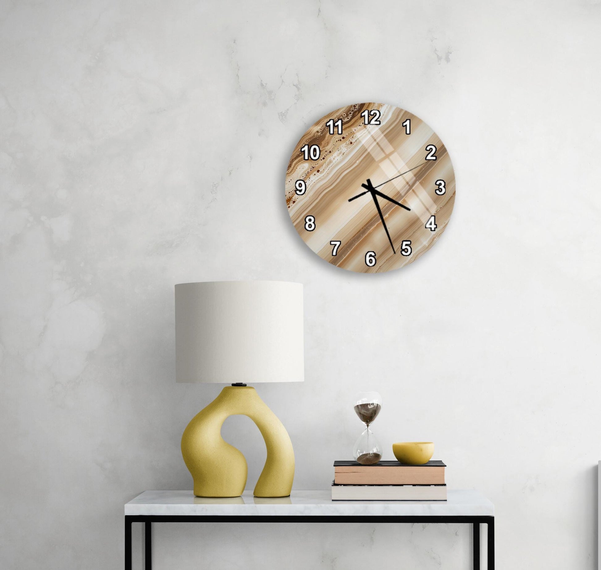 a modern living room with a white marble wall, a round clock with a brown and white striped design, a yellow lamp with a unique curved base, and a small table with a book and a glass of wine.