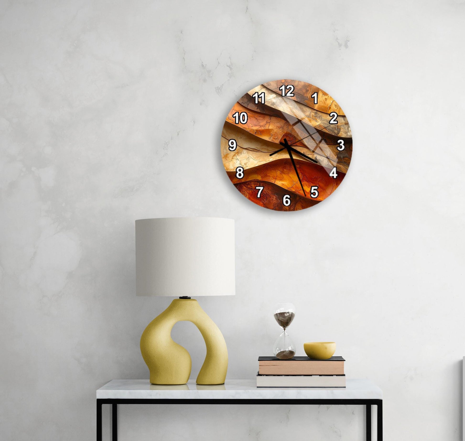 a modern wall clock with a unique design, a yellow table lamp, a stack of books, and a glass of wine on a white table.