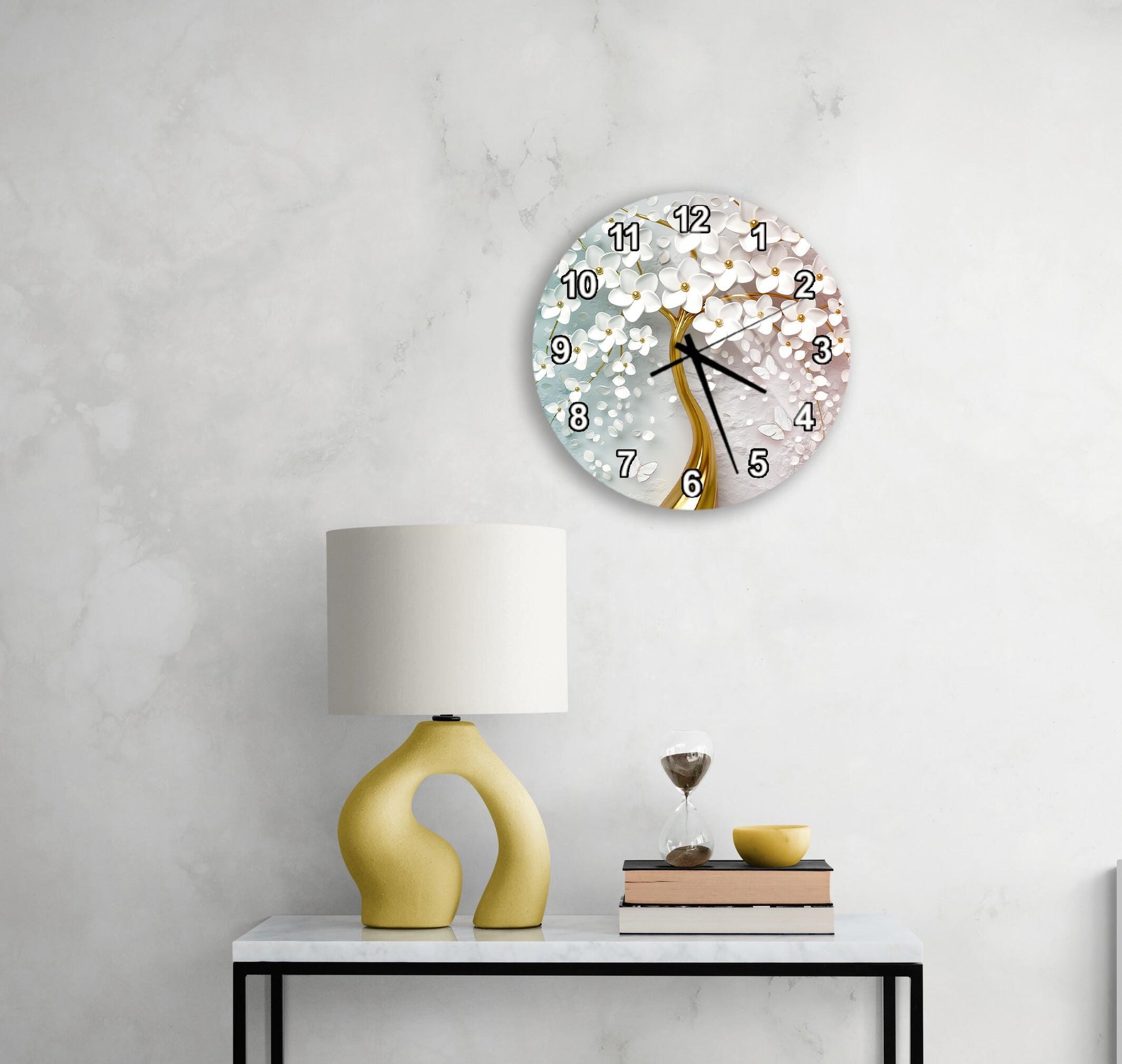 a modern living room with a white marble wall, a round clock with a floral design, a yellow lamp with a unique curved base, and a small table with a book and a glass of water.
