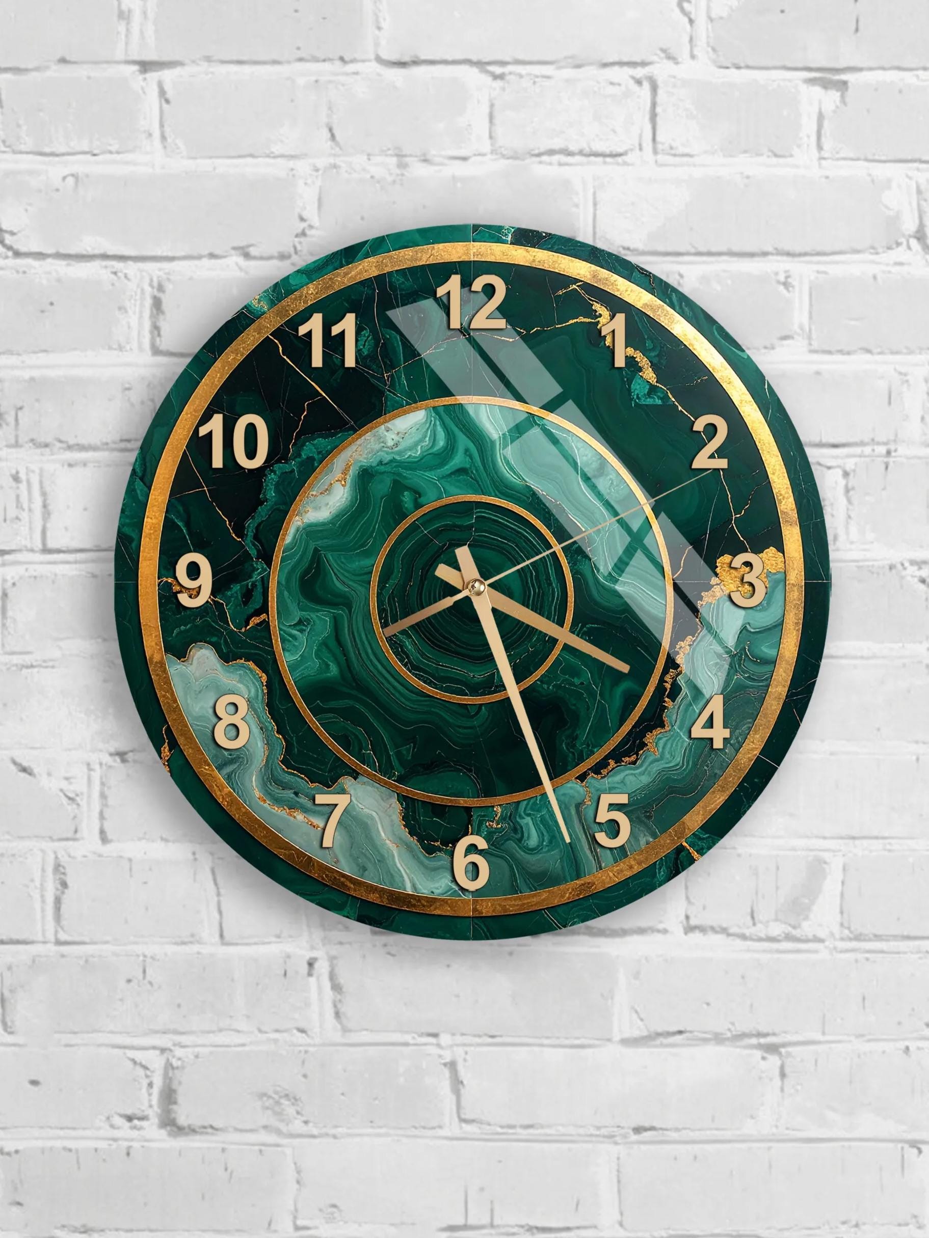 A wall clock with a green marble-like design and gold accents, mounted on a white brick wall.