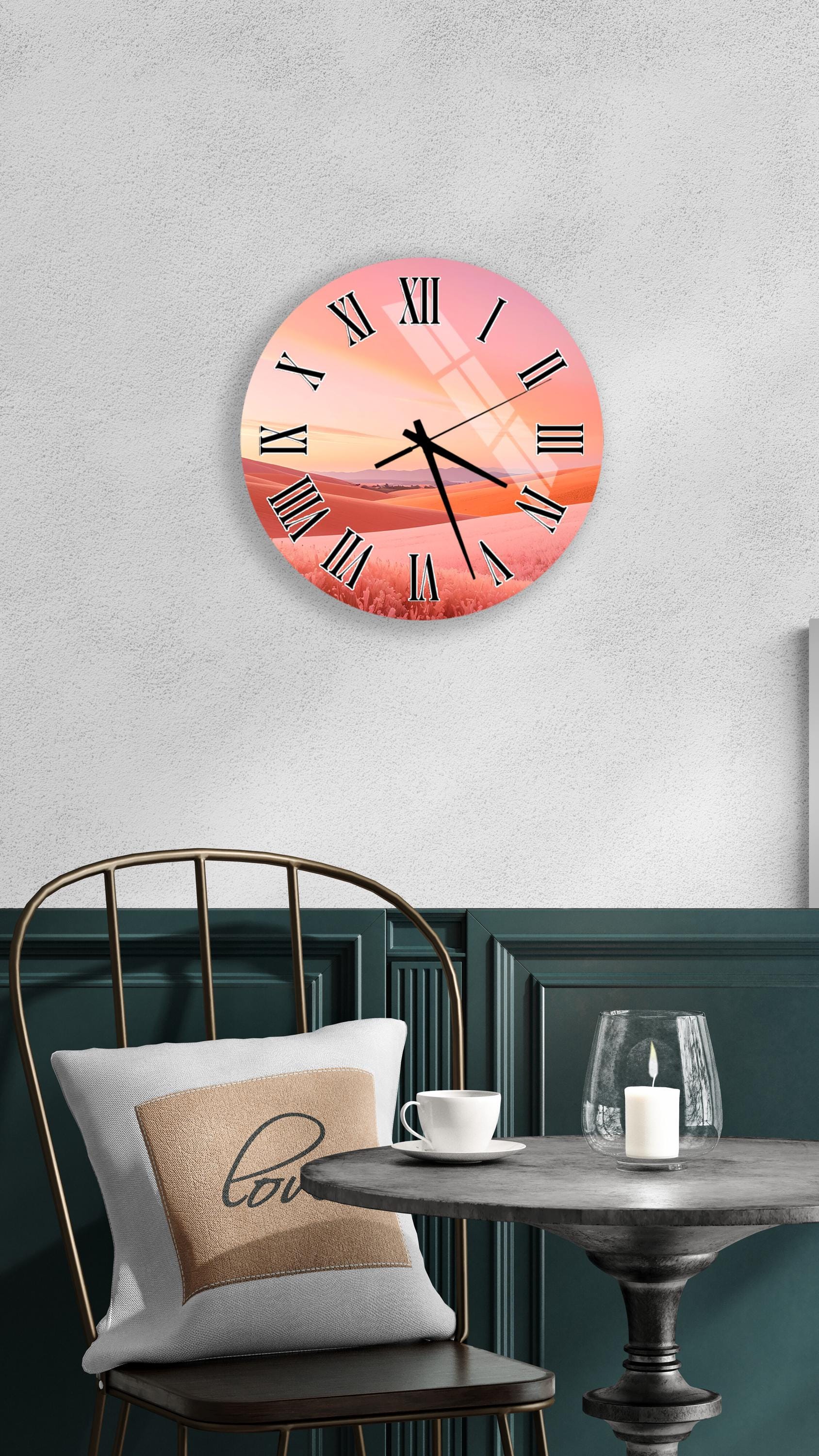 a wall clock with a sunset-like design, mounted on a wall above a table with a white tablecloth and a candle.