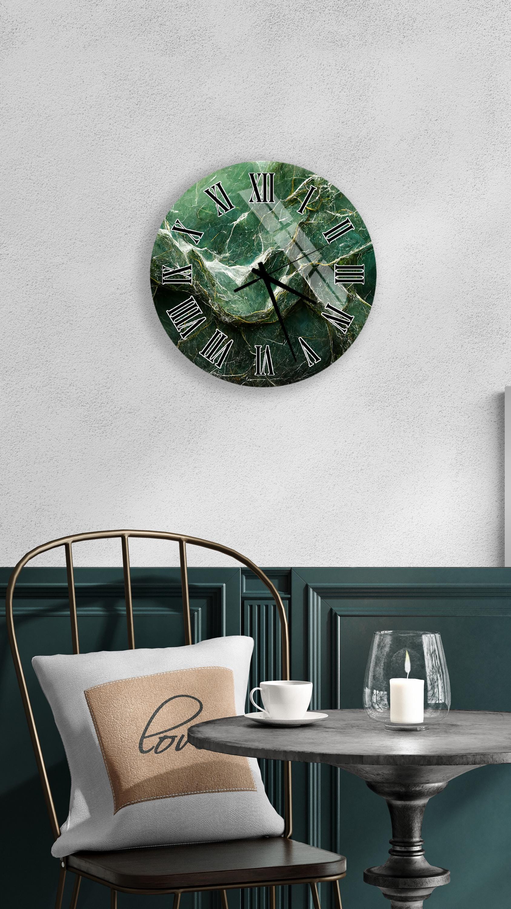 a round wall clock with a green marble-like design, mounted on a white wall above a dining table with a white tablecloth. The table is set with a white cup and a candle, creating a cozy and inviting atmosphere.