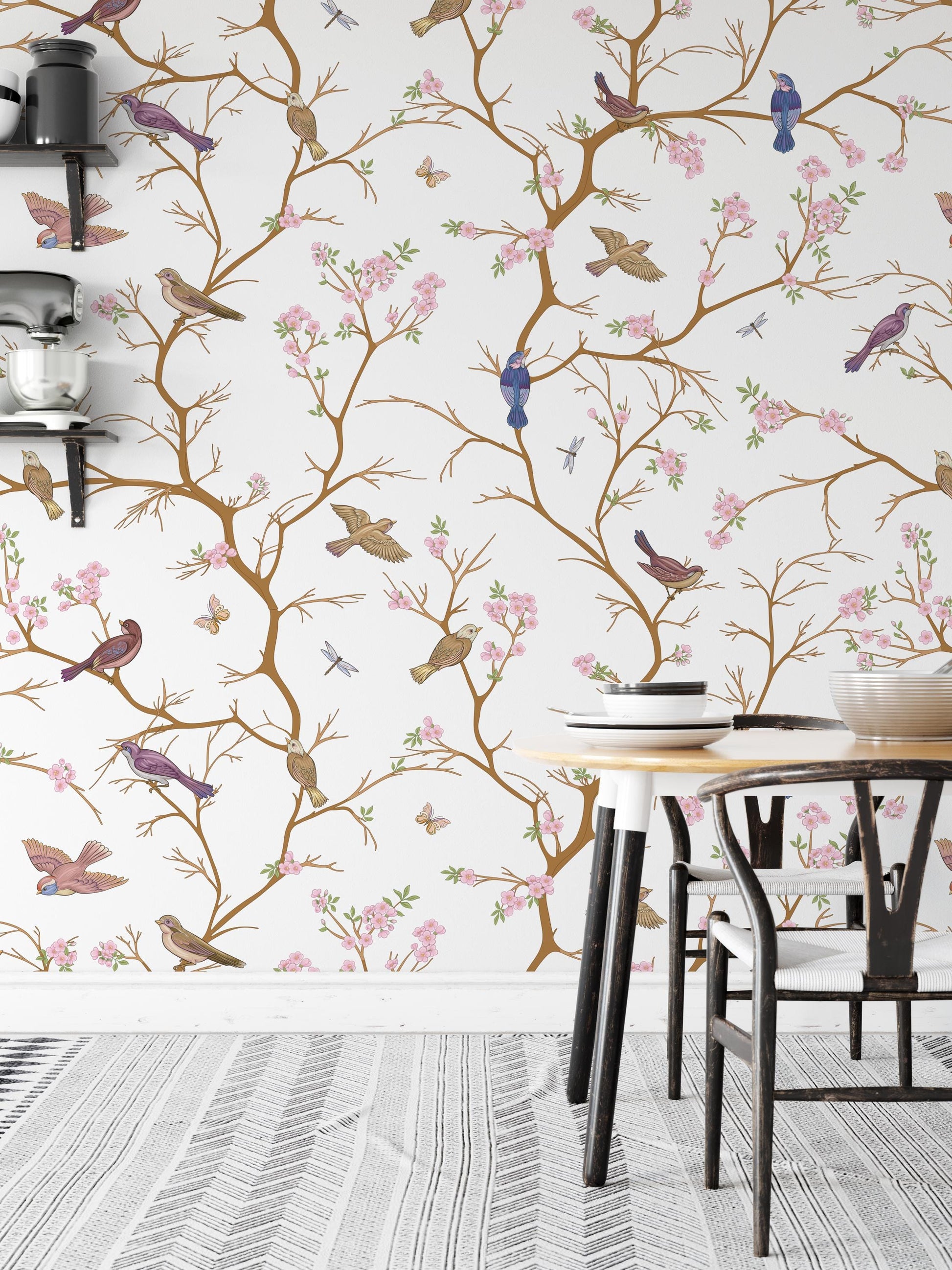 a wallpapered wall with a repeating pattern of birds perched on branches and flowers, creating a whimsical and nature-inspired design. In the foreground, there is a dining table with chairs, suggesting a cozy dining area.