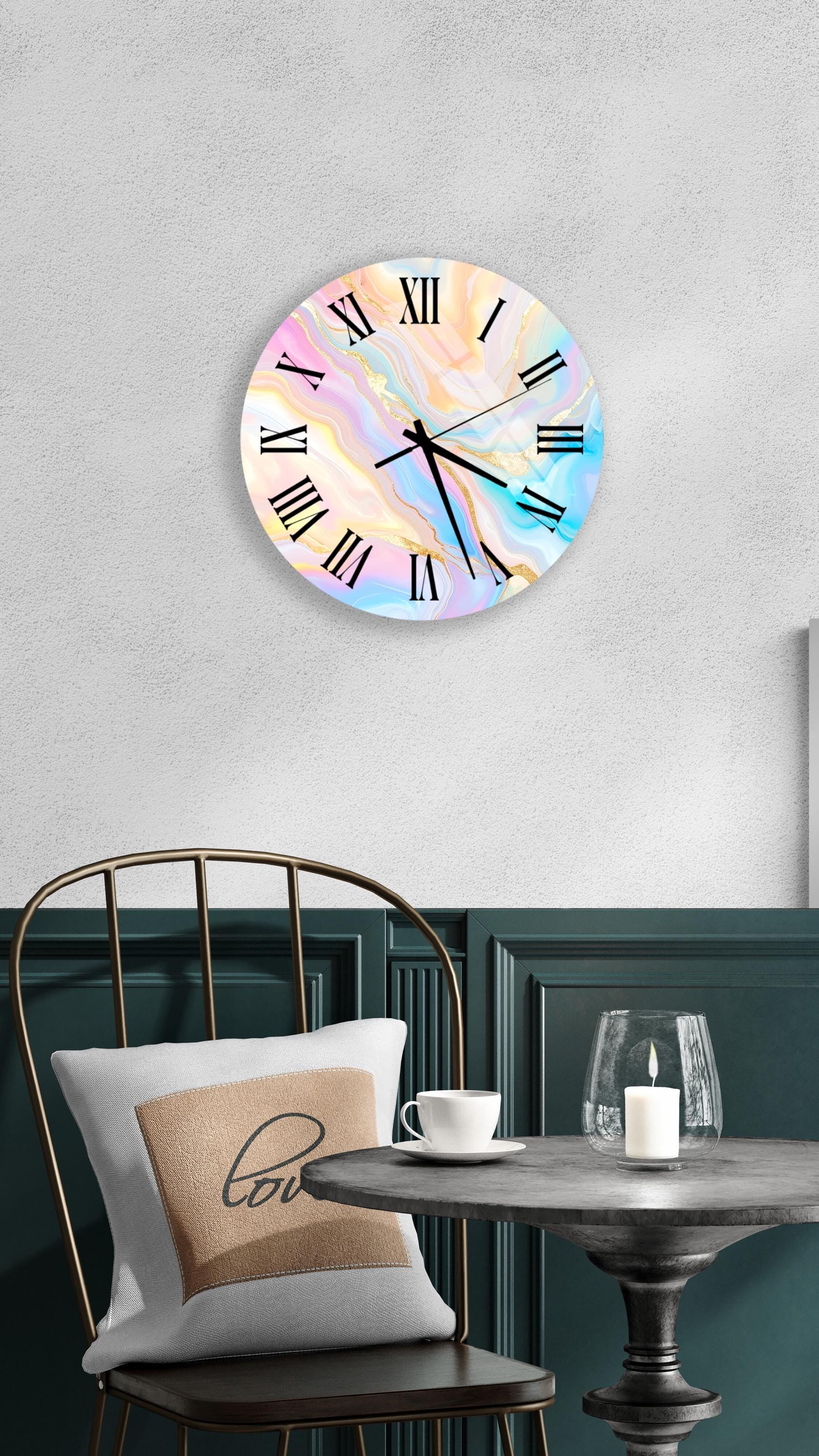 a wall clock with a marble-like design, a white table with a candle and a cup, and a chair with a pillow on it.
