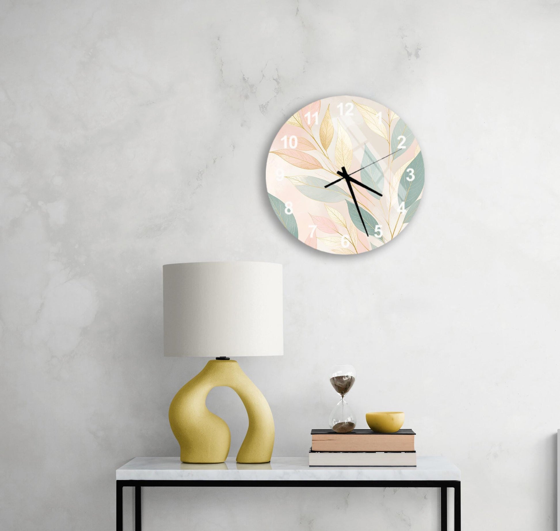 a white wall with a round clock displaying a floral design, a yellow lamp with a unique, curved base, and a small table with a book and a glass of water.