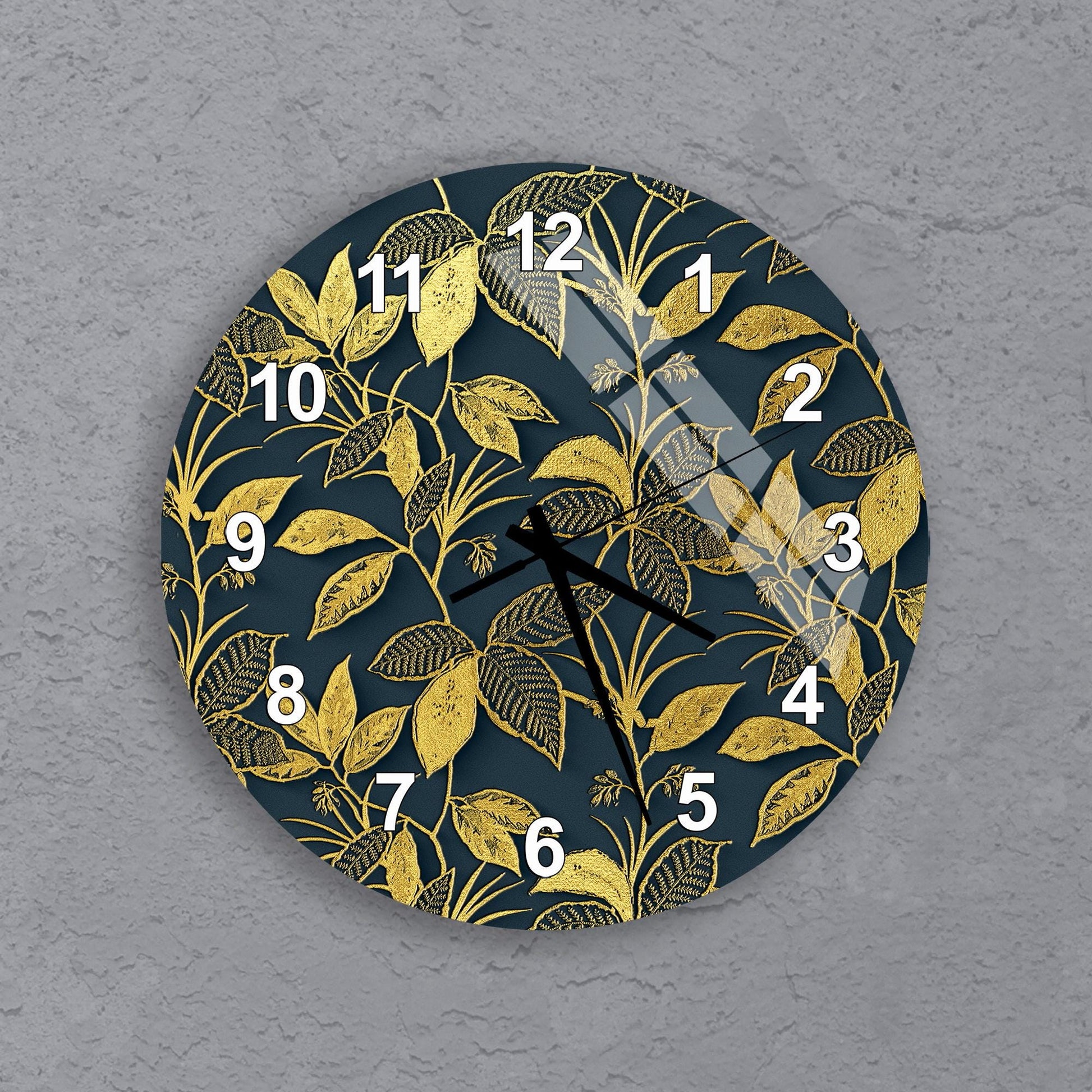 A wall clock with a dark blue background and a gold leaf pattern.