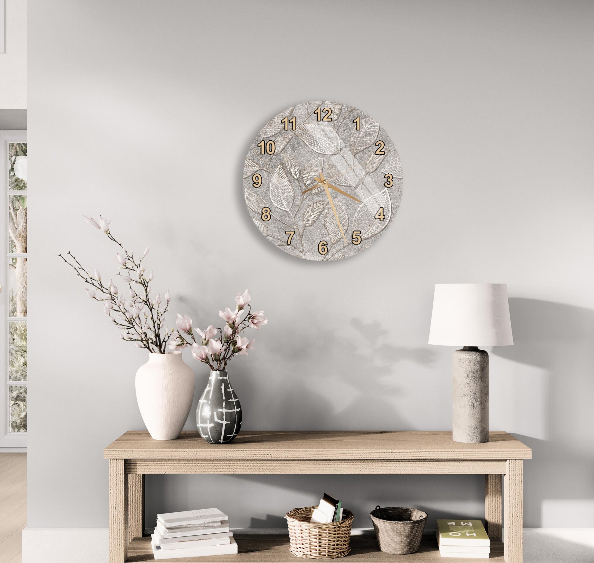 a modern living room with a wooden console table, a round wall clock with a leaf design, a vase with pink flowers, and a lamp.