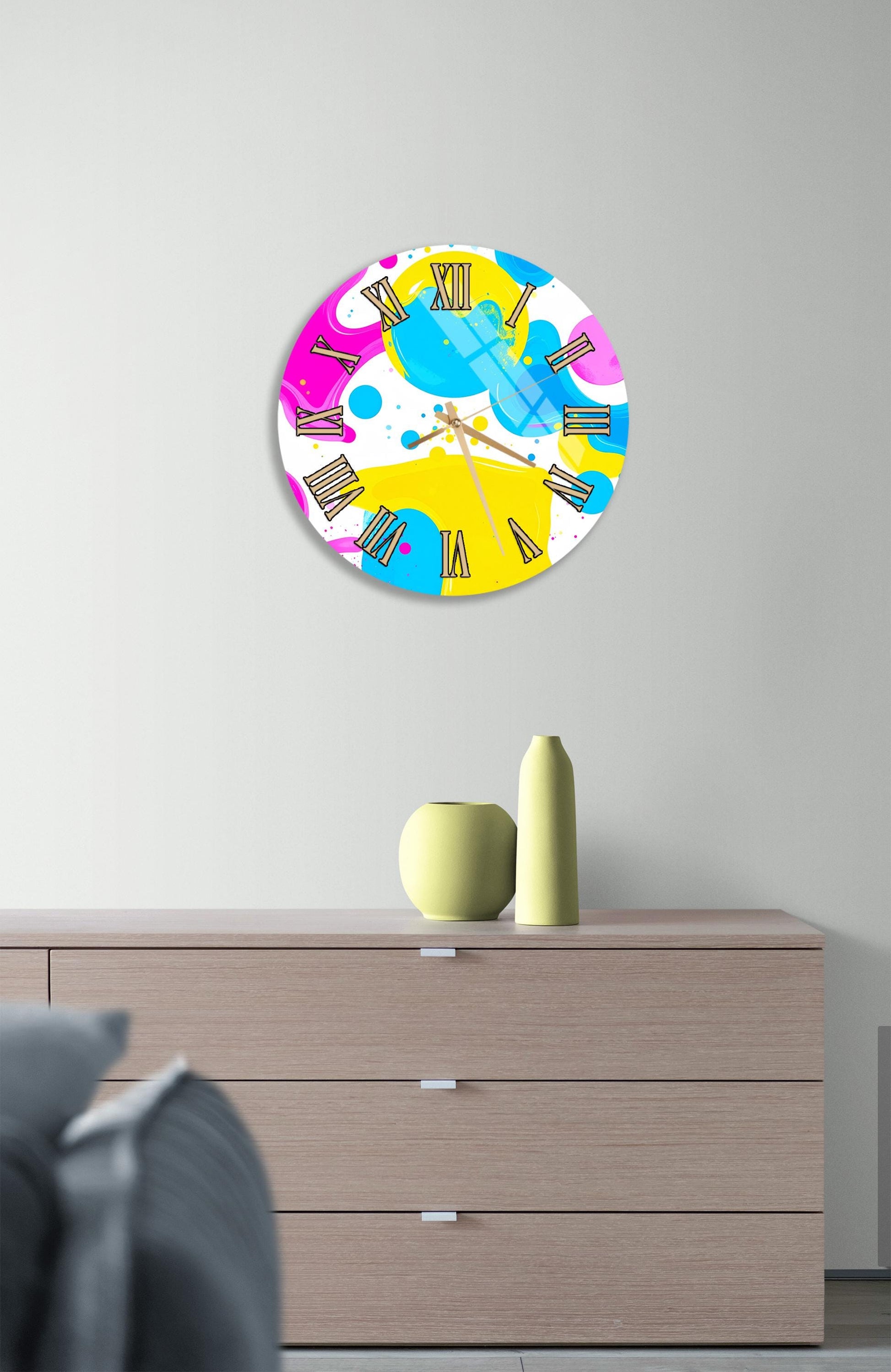 a colorful abstract clock with a vibrant design on a wall above a wooden dresser.