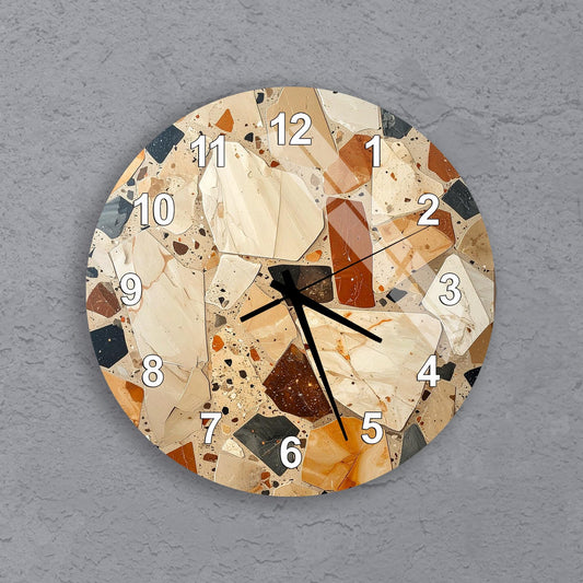 A wall clock with a mosaic design made up of various colored tiles, including shades of brown, beige, and orange. The clock face is white with black numbers and hands.