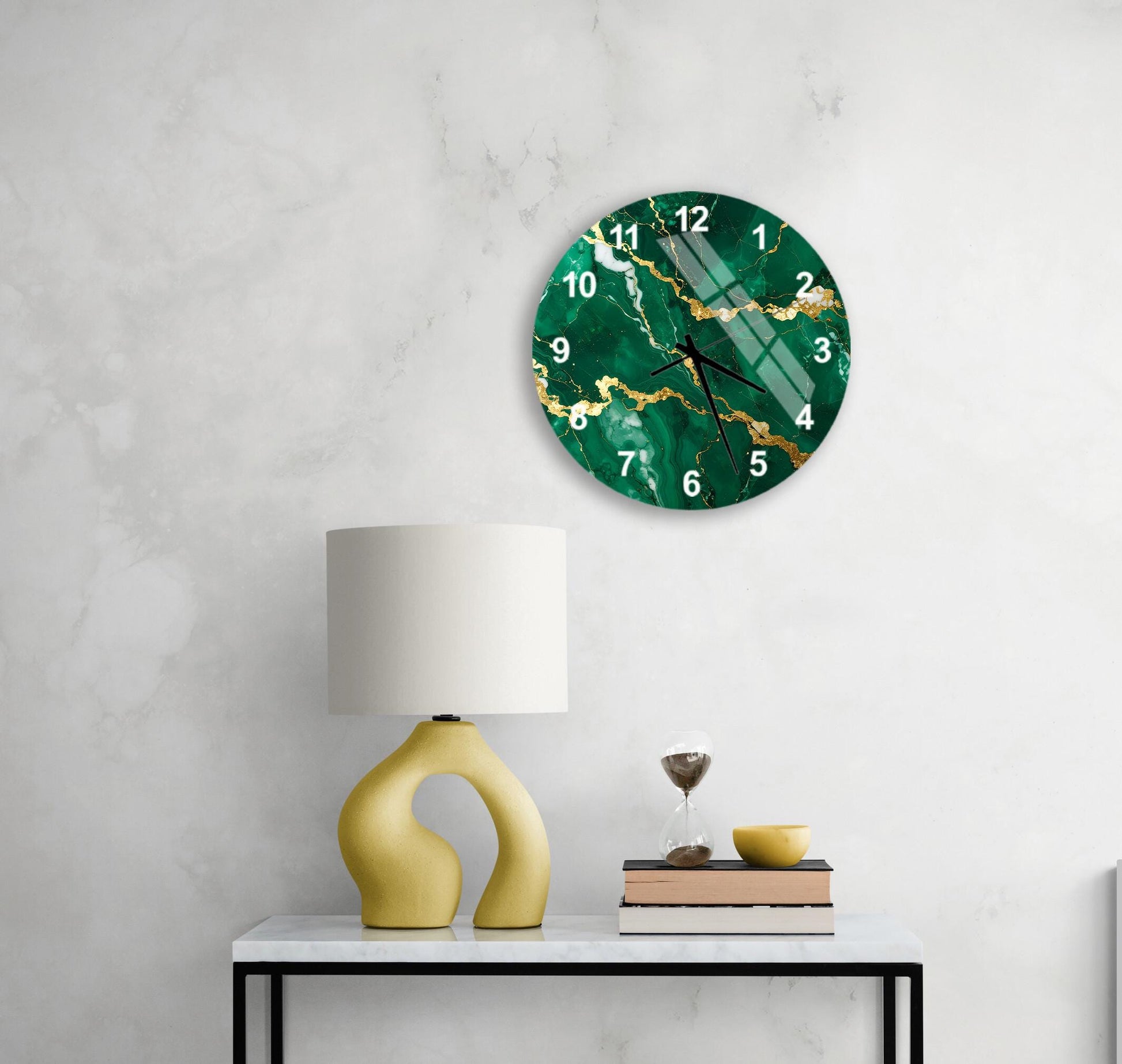 a modern living room with a green marble clock hanging on the wall above a white table. The table has a yellow lamp and a stack of books, creating a cozy and stylish atmosphere.