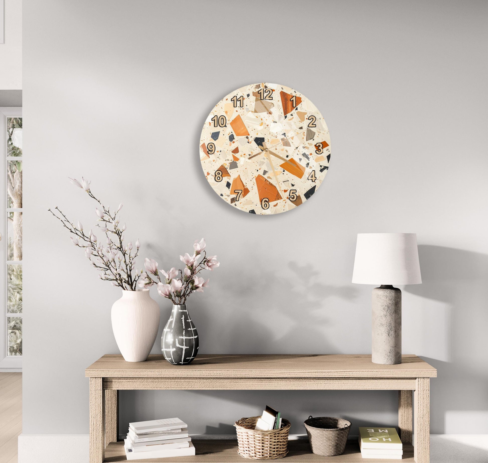 a wooden table with a lamp, a vase with flowers, and a clock on the wall above it.