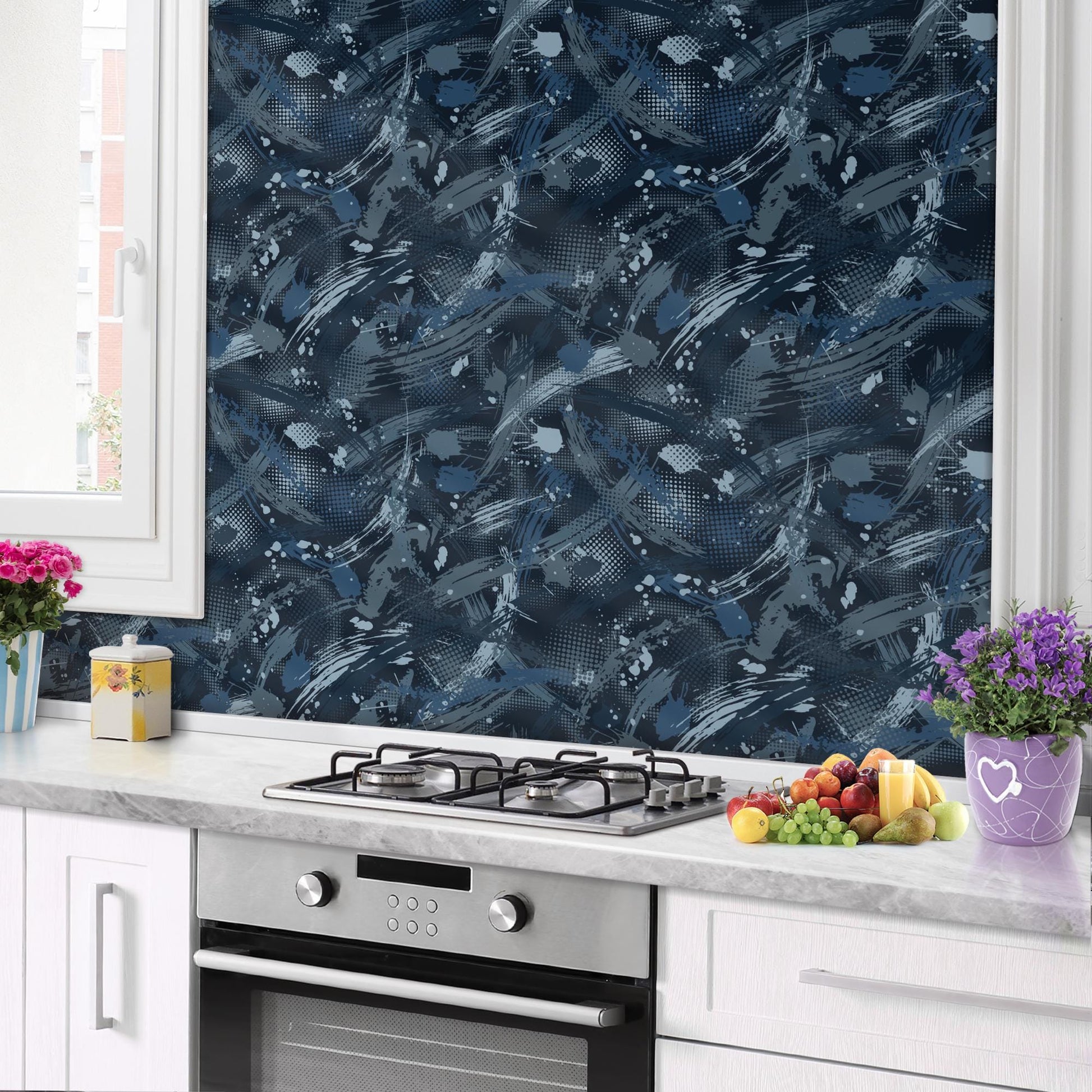 a kitchen counter with a stove, a vase of flowers, and a bowl of fruit. The counter is white and has a black backsplash with a blue abstract pattern.