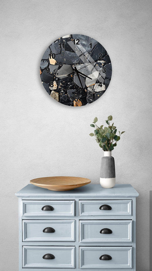a wall clock with a black and white design, mounted on a wall above a light blue dresser with six drawers. The dresser also has a wooden bowl and a vase with greenery on it.