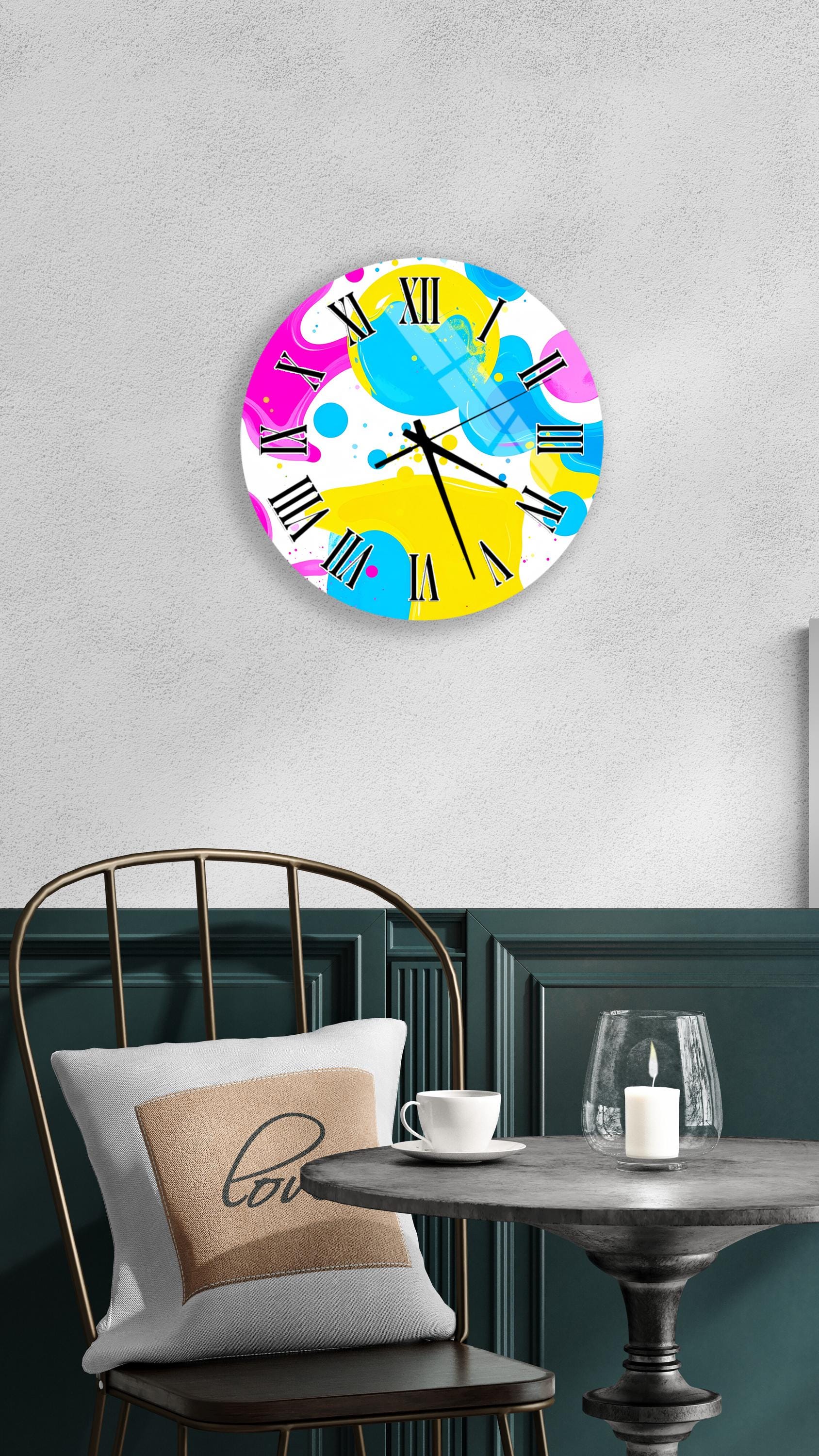 a colorful abstract clock with a white face and black hands, hanging on a wall above a table with a white tablecloth.