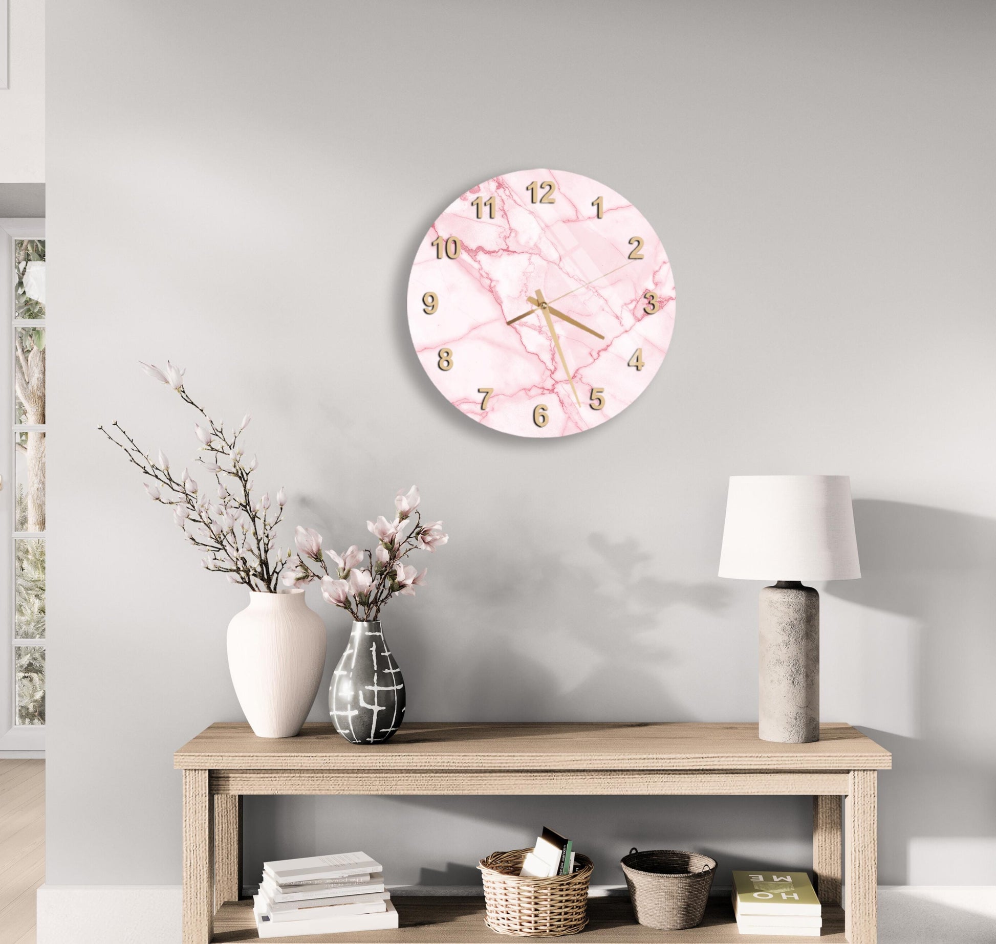 a modern and minimalist living room with a round wall clock, a wooden table with a lamp, a vase with flowers, and a stack of books.