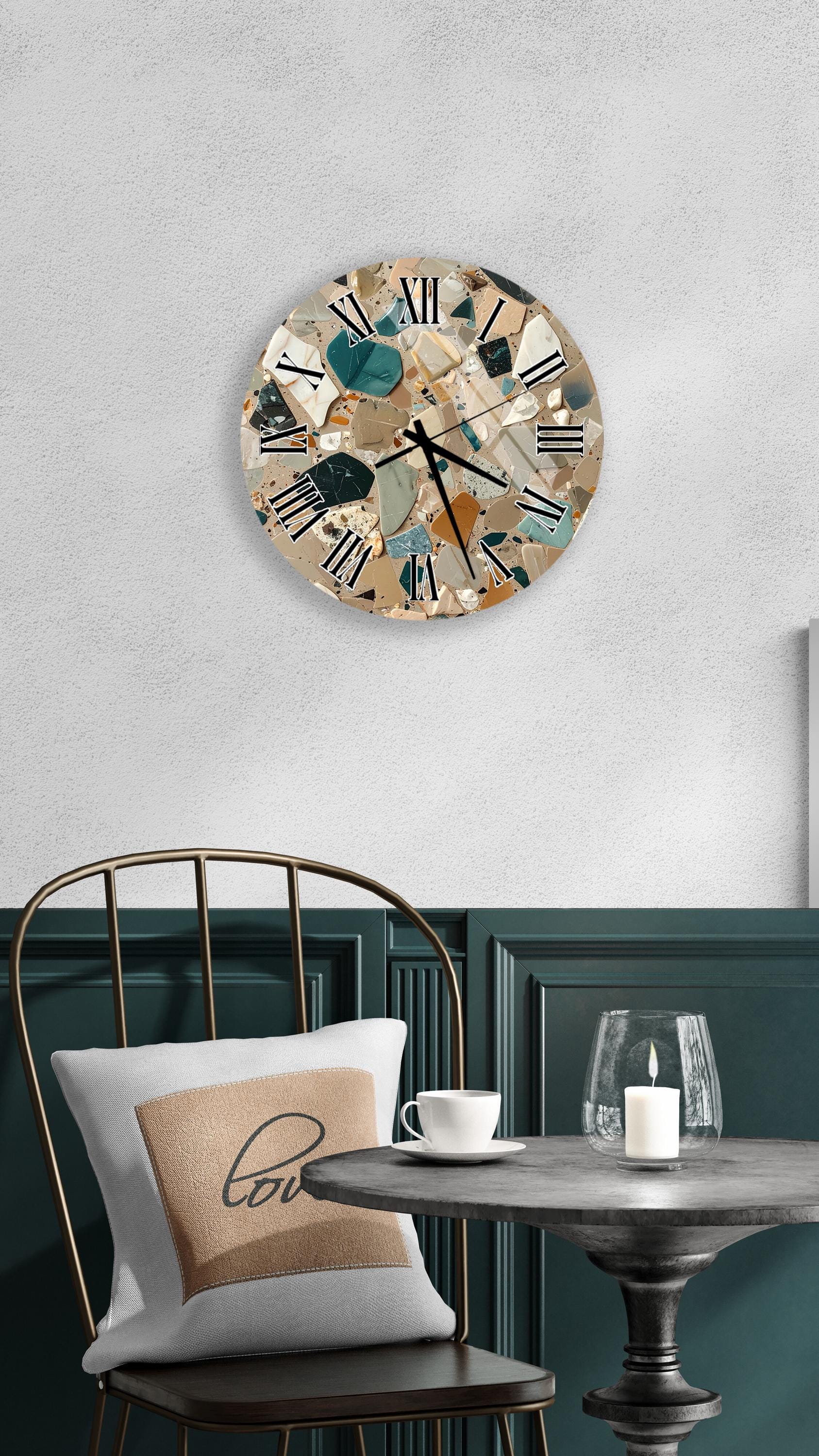 a modern and stylish interior design with a round wall clock featuring a mosaic pattern, a white table with a candle and a cup, and a black metal chair with a white pillow.