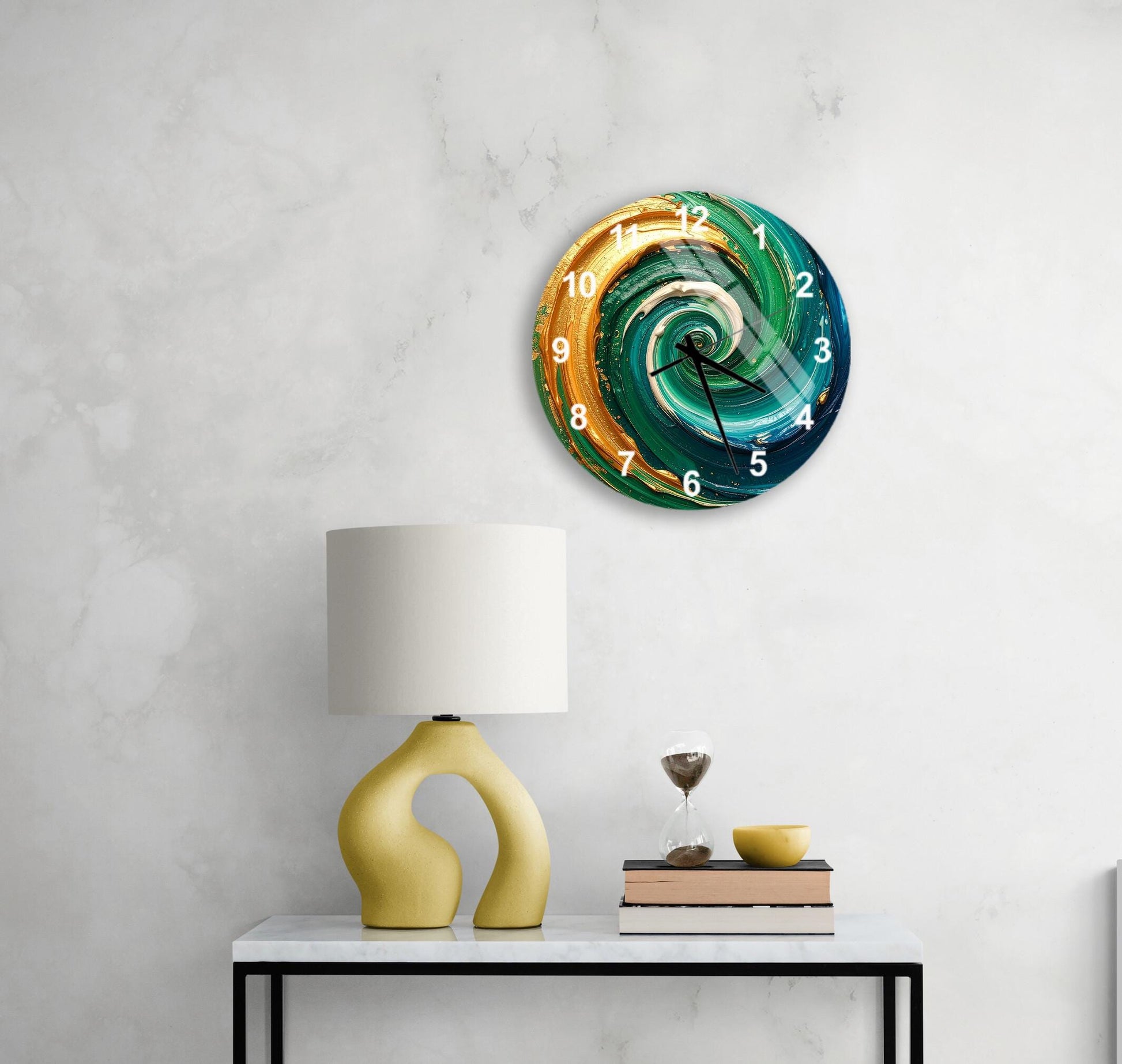 a modern, abstract wall clock with a swirling design in shades of blue, green, and orange. Below the clock, there is a yellow lamp with a unique, curved base, and a stack of books on a white table.