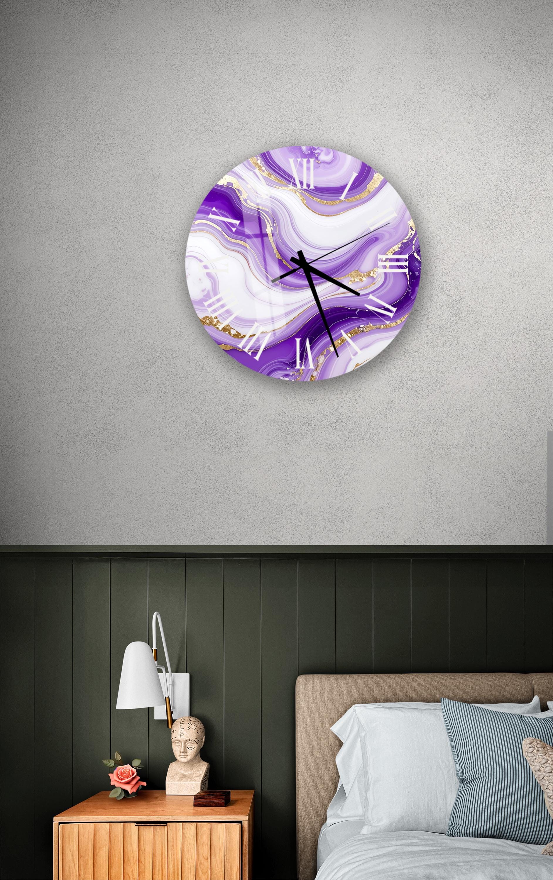 a bedroom setting with a large purple and gold wall clock hanging above a bed. The clock has a marble-like design and is mounted on a gray wall. Below the clock, there is a wooden nightstand with a lamp and a small statue.