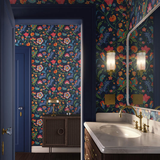 a bathroom with a floral wallpaper, a white sink, and a wooden vanity with a lamp. The walls are covered in a vibrant, colorful floral pattern, creating a lively and cheerful atmosphere.