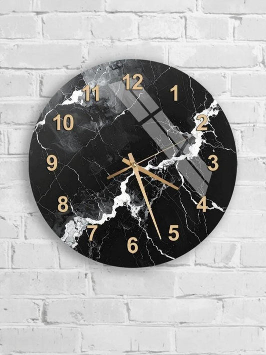 A black and white marble wall clock with gold numbers and hands is mounted on a white brick wall.