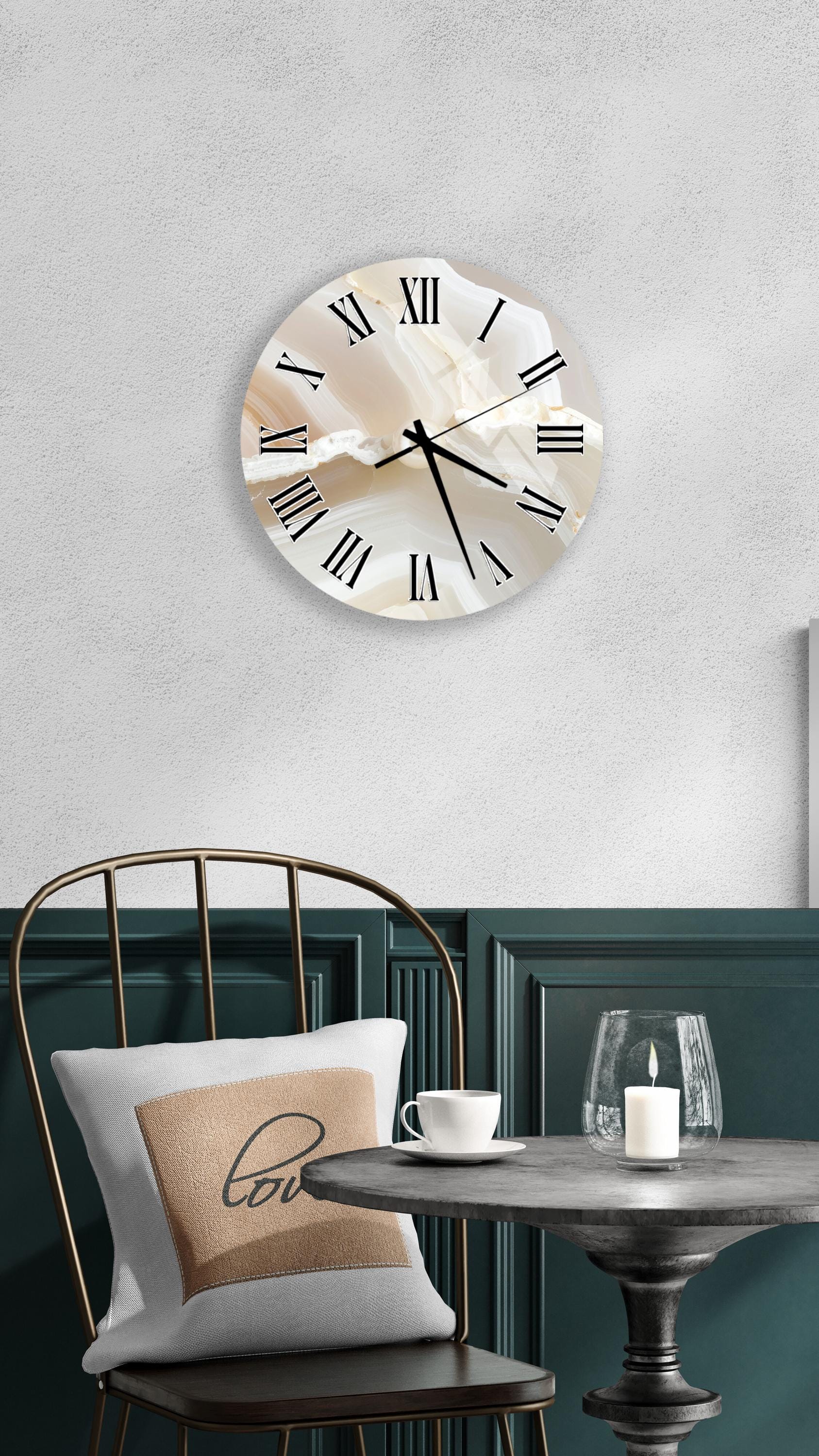a modern and minimalist interior design with a round wall clock, a white table with a candle, and a black chair with a pillow.