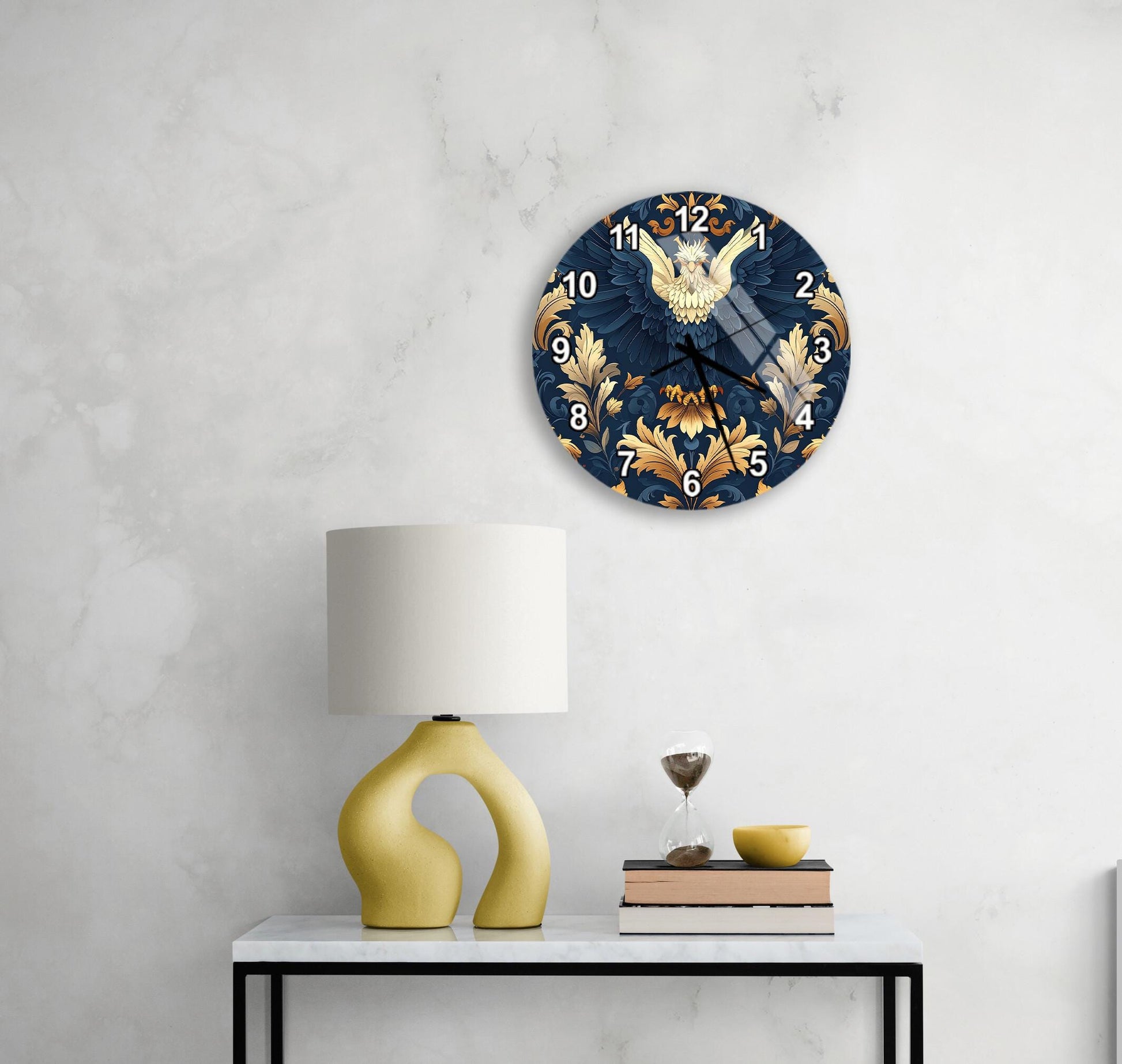 a stylish clock with a blue and gold design, mounted on a wall above a white table with a yellow lamp and a stack of books.