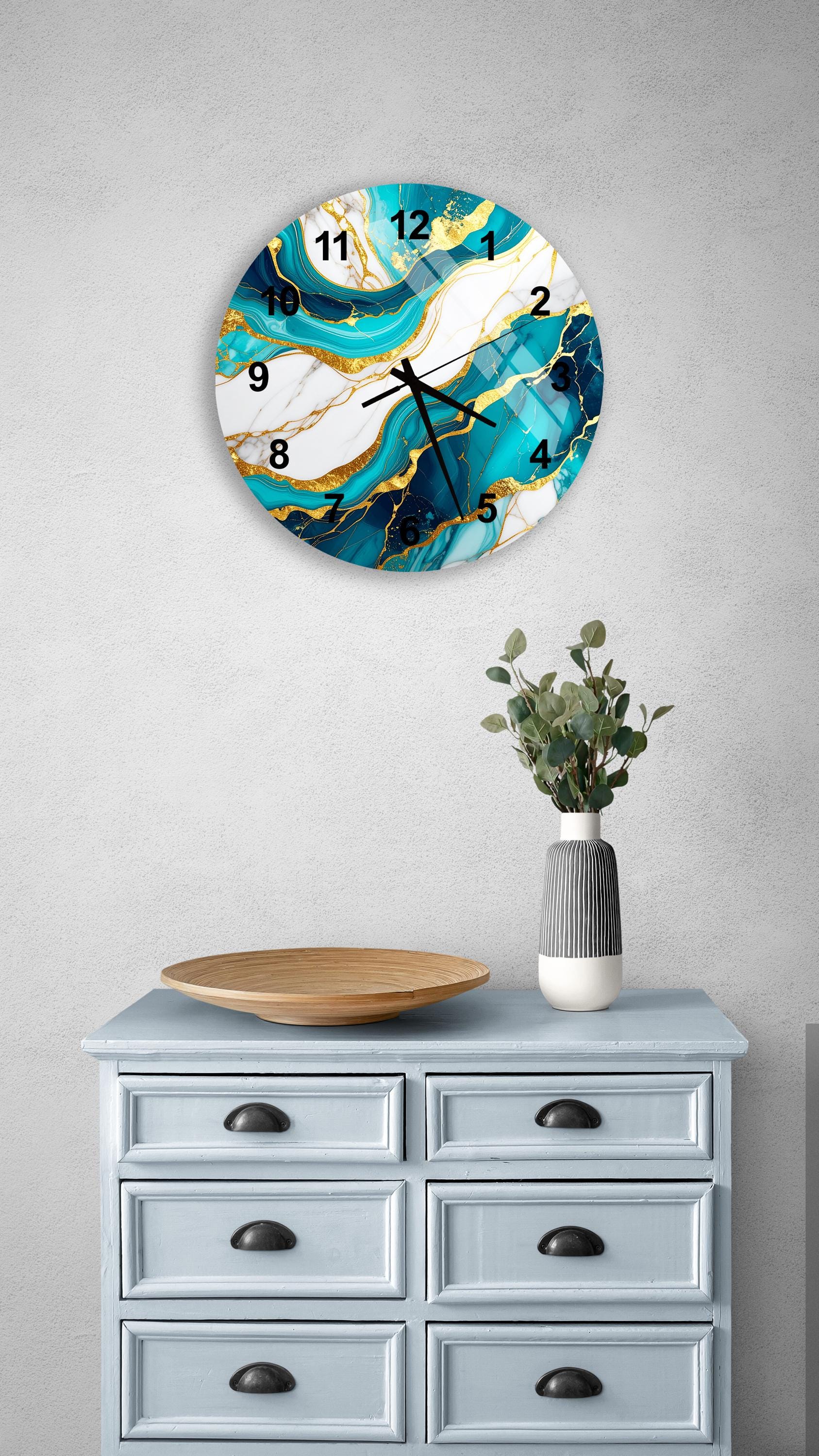 a wall clock with a marble-like design, mounted on a wall above a light blue dresser with six drawers. The dresser also has a vase with greenery on it, and there is a wooden plate on top of it.