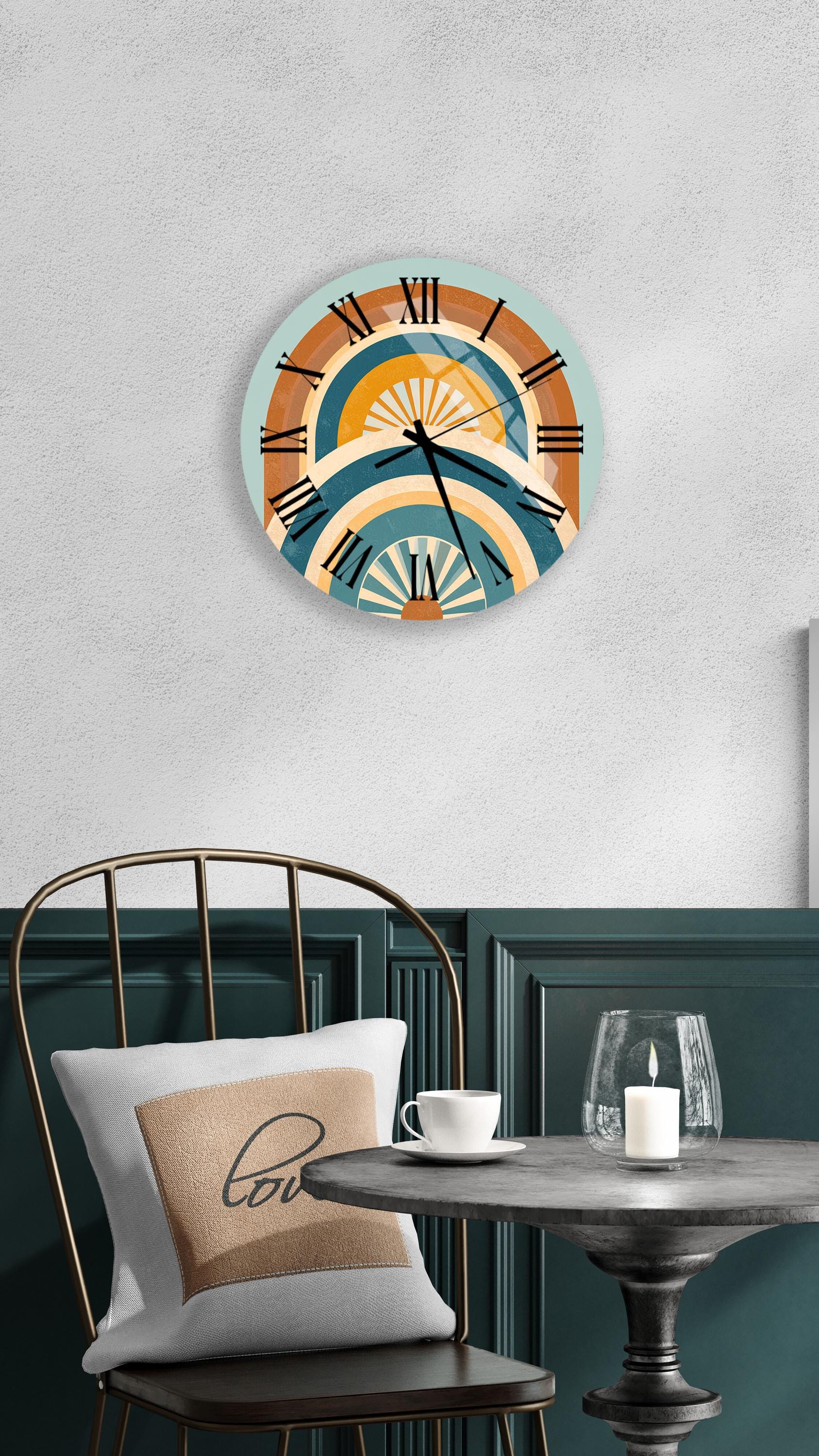 a wall clock with a colorful design, a white table with a candle and a cup, and a black chair with a pillow.