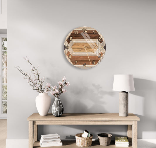 a wooden clock with a geometric design, mounted on a wall above a wooden table with various decorative items, including a vase with flowers, a lamp, and a stack of books.