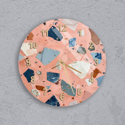 A round wall clock with a unique, colorful design featuring various shapes and textures, including numbers and other decorative elements.