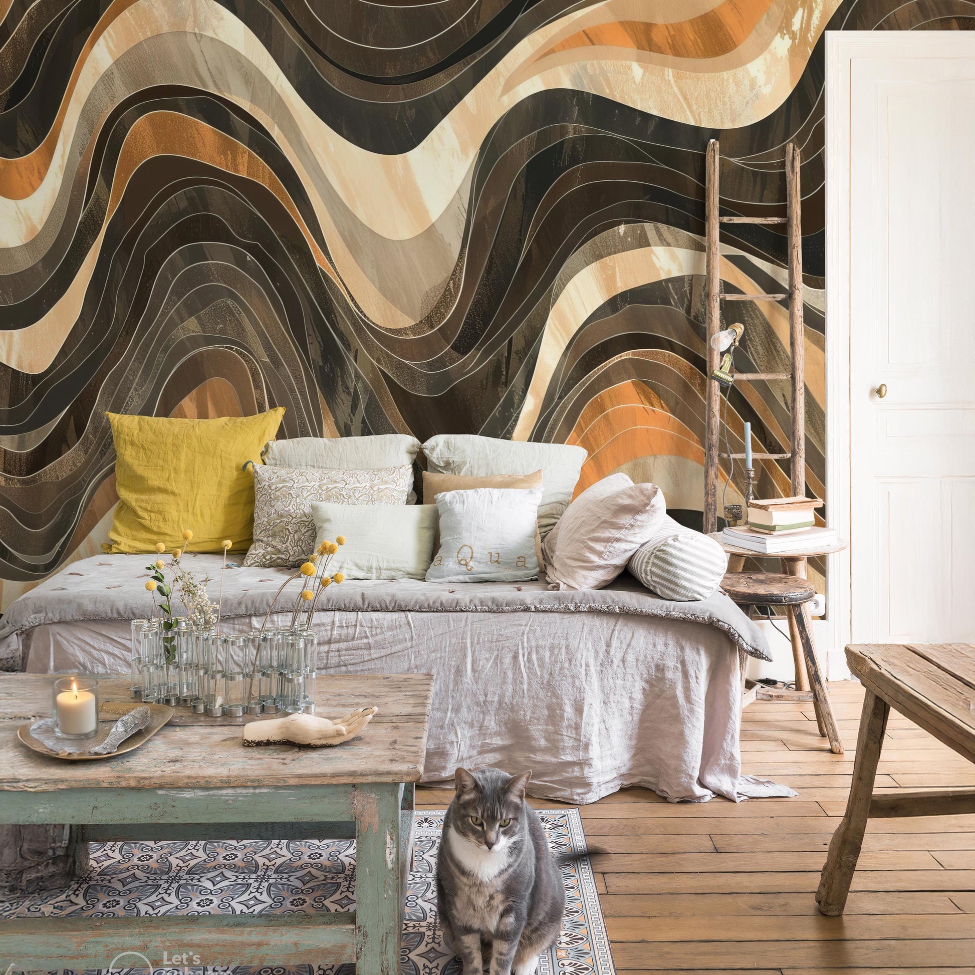 a cozy living room with a large abstract wall mural featuring wavy lines in various shades of brown, orange, and beige. The room is furnished with a gray sofa adorned with yellow and white pillows, a wooden coffee table, and a wooden ladder. A cat is sitting on the floor in front of the sofa, and a vase of flowers is placed on the coffee table.