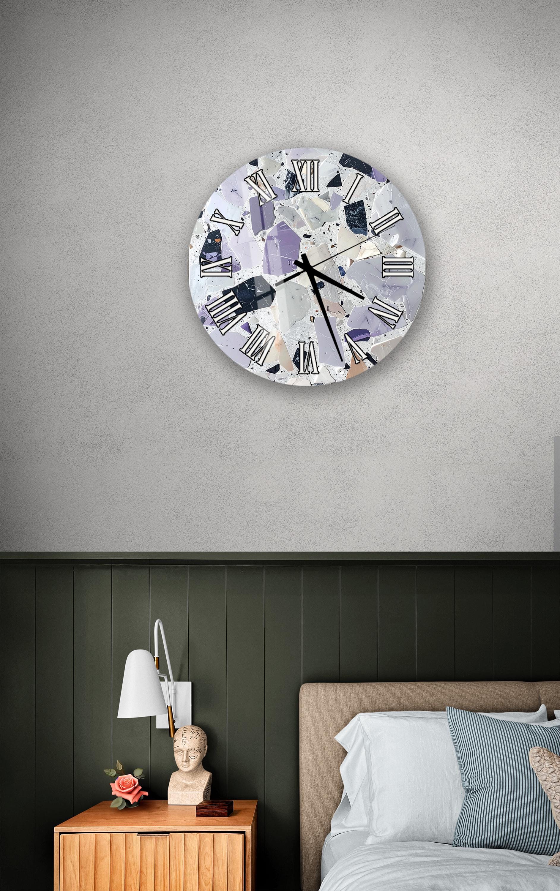 a bedroom setting with a clock on the wall, a nightstand with a lamp, and a bed with white sheets and pillows.