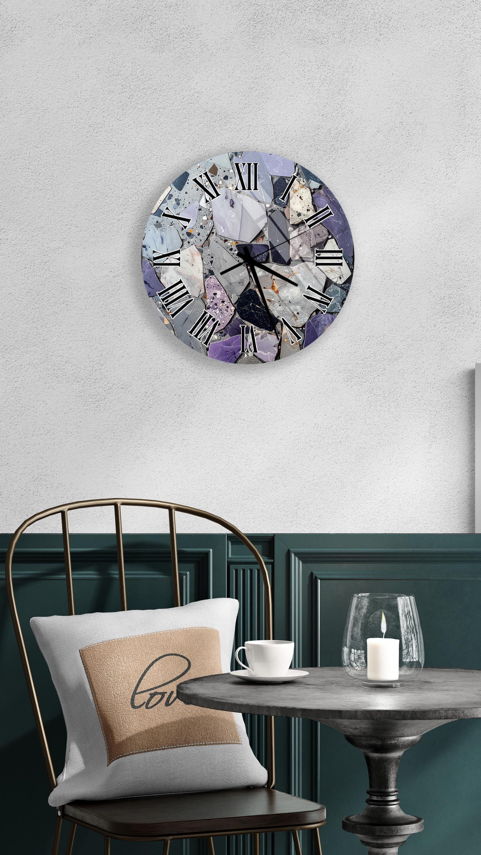 a round clock with a mosaic design on the wall above a table with a white tablecloth and a candle on it.
