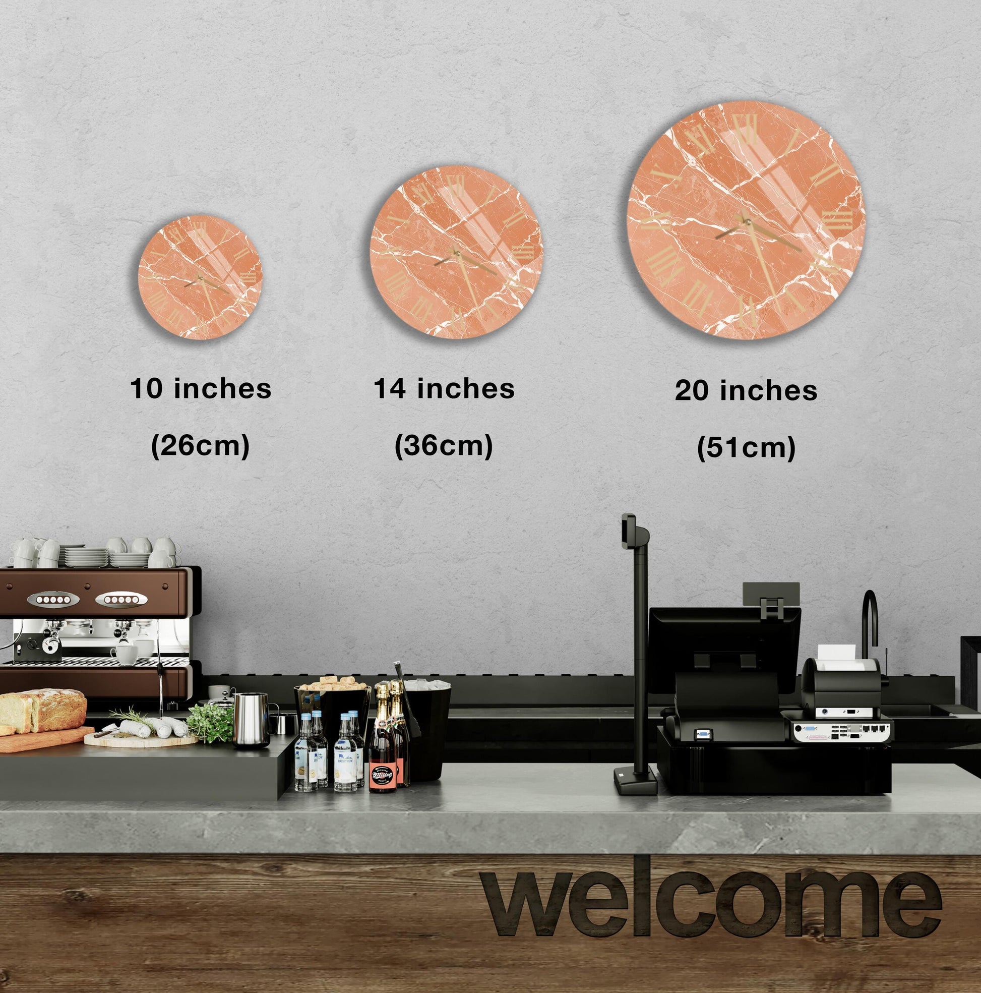 a counter with a cash register, a coffee machine, and various food items such as bottles and bread. Above the counter, there are three round wall clocks of different sizes, each displaying a different time. The wall behind the counter has a welcoming message written on it.