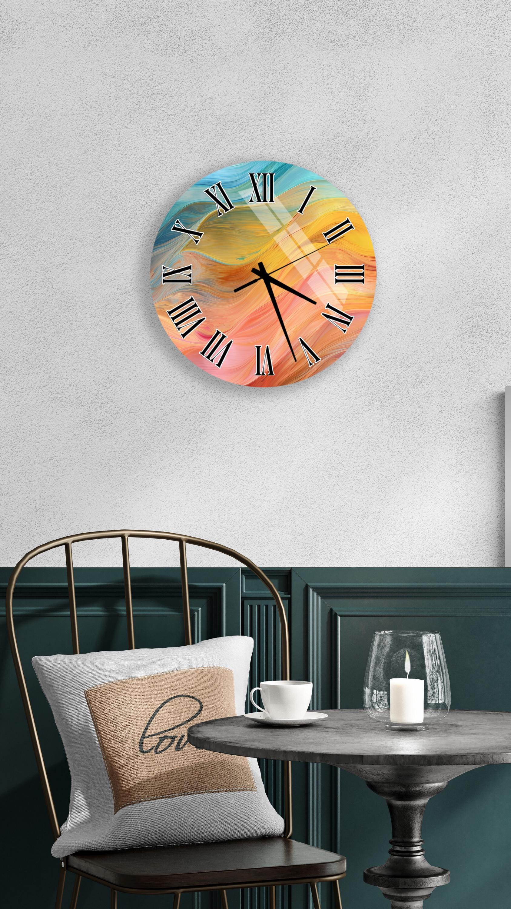 a wall clock with a colorful abstract design, a white table with a candle and a cup, and a black chair with a pillow.