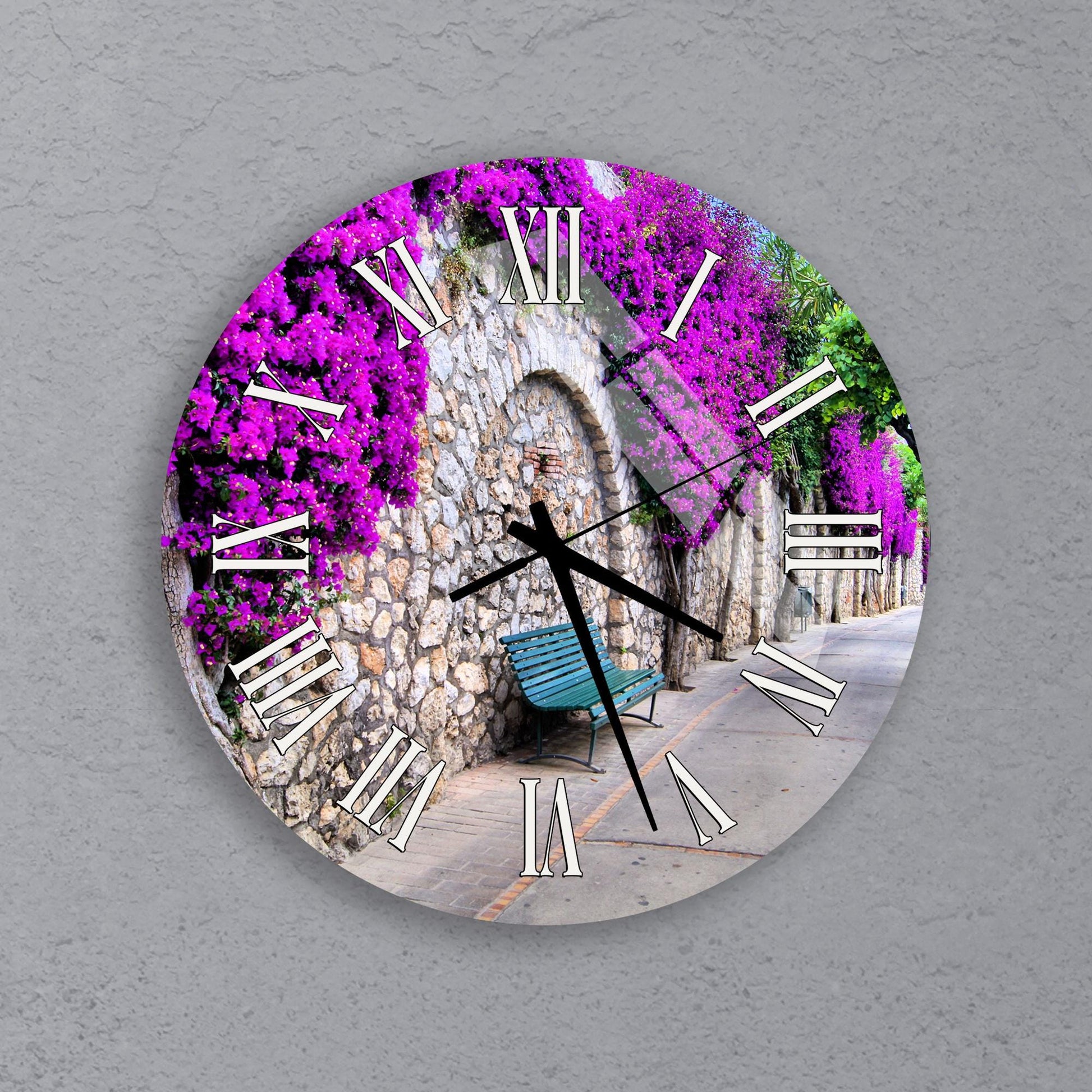 A clock with a design featuring a stone archway and a bench, surrounded by purple flowers.