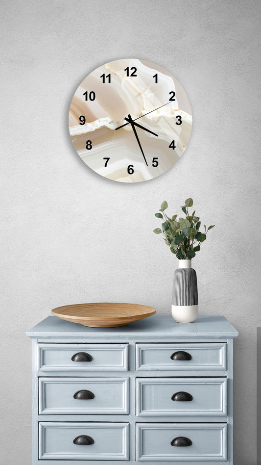 a wall clock with a marble-like design, a wooden bowl, and a vase with greenery on a light blue dresser.