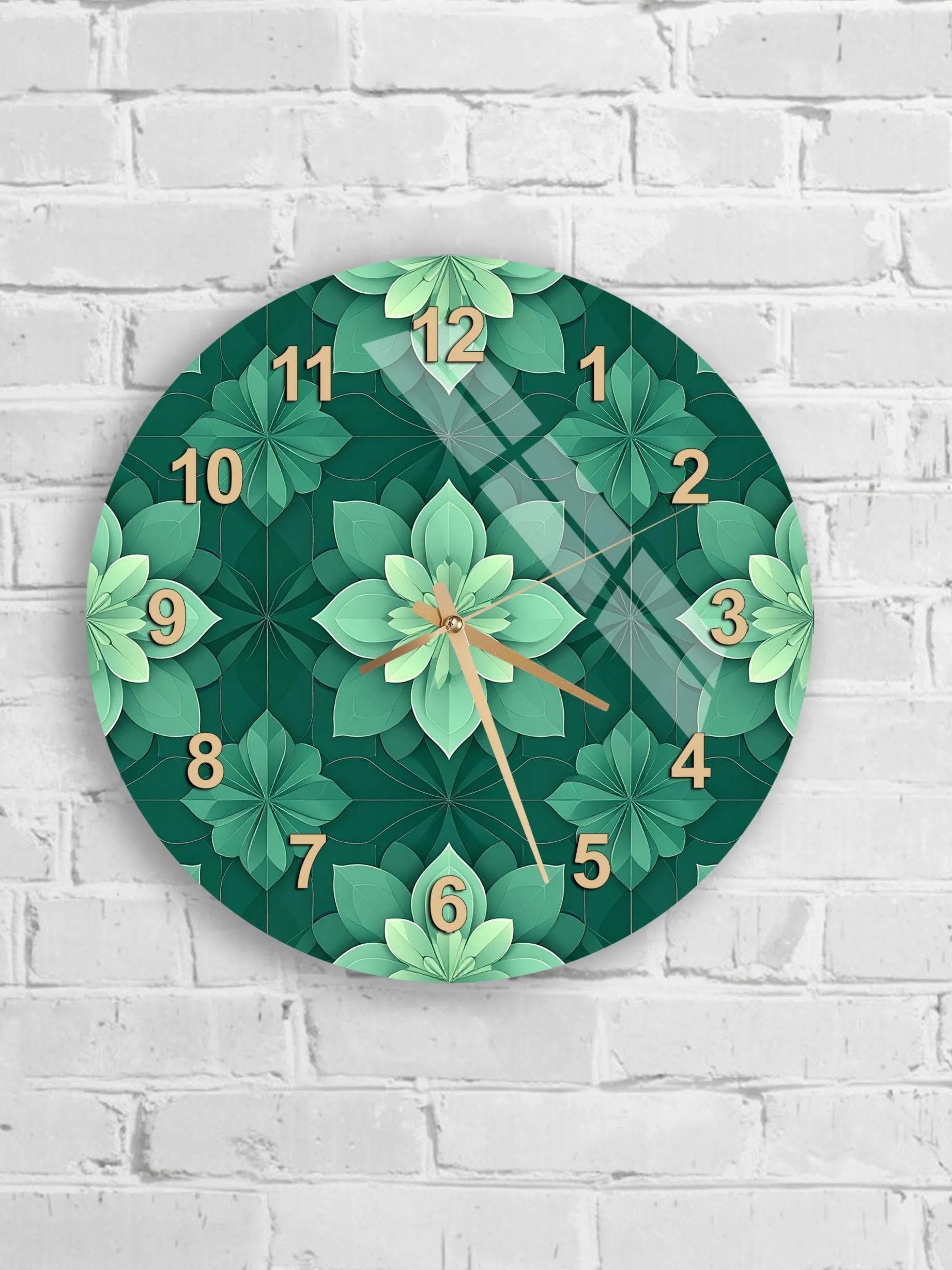 A wall clock with a green floral pattern and gold numbers is mounted on a white brick wall.