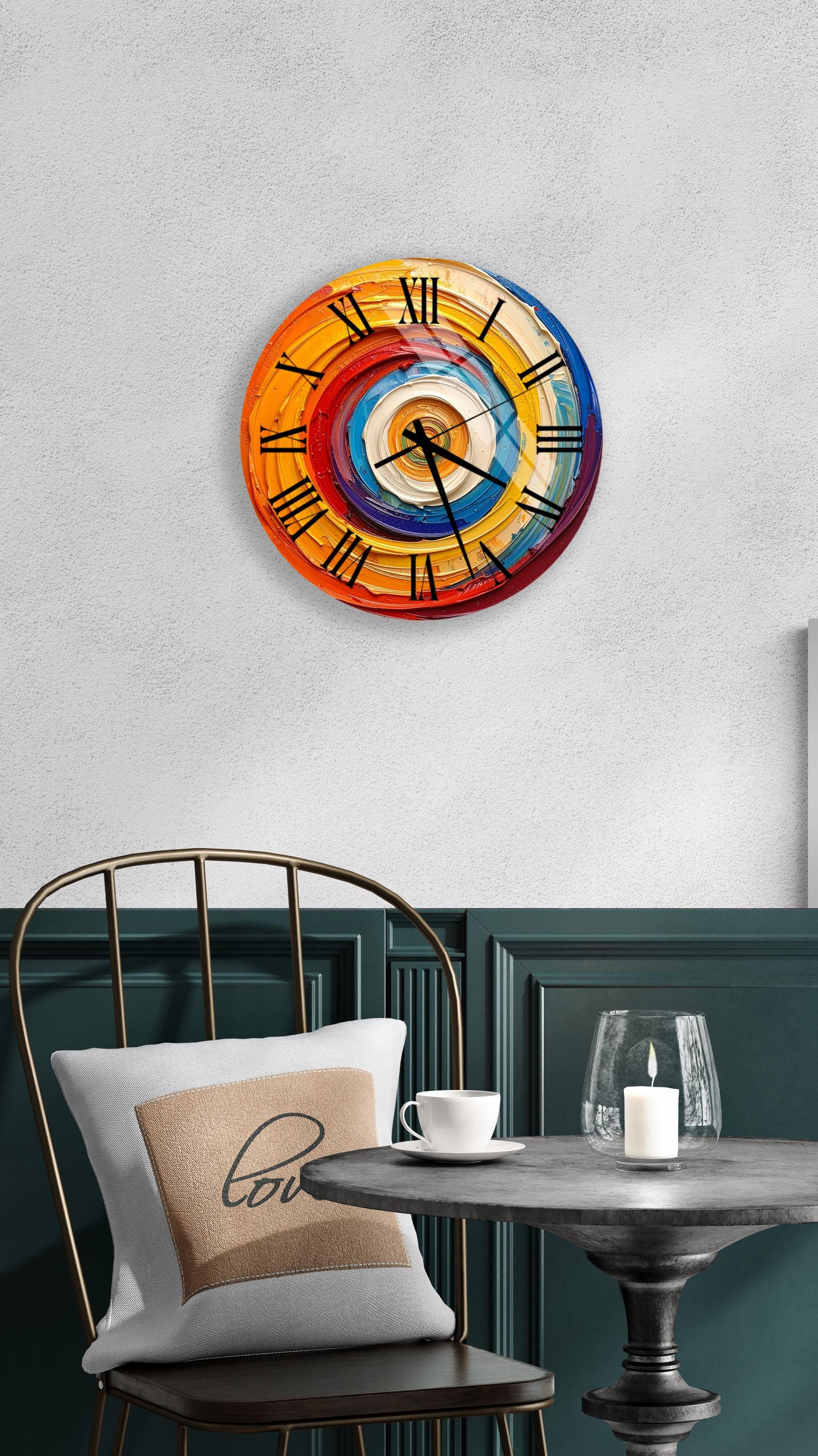 a wall clock with a colorful, abstract design, mounted on a wall above a table with a white tablecloth.