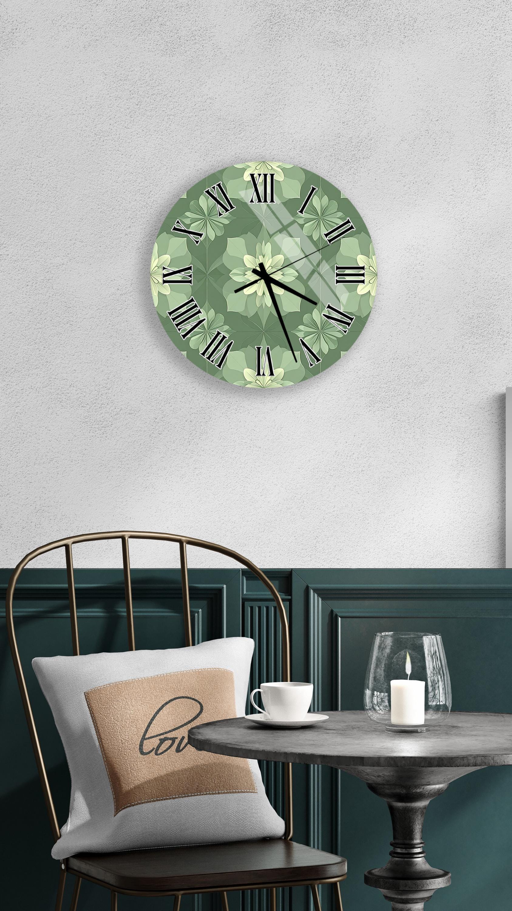 a wall clock with a green floral design, a white table with a candle and a cup, and a black chair with a pillow.