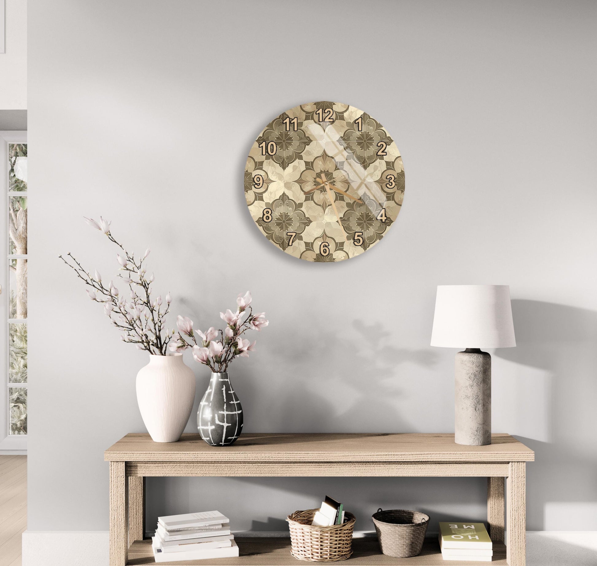 a modern living room with a wooden console table, a round wall clock with a floral design, a lamp, a vase with pink flowers, and a stack of books.