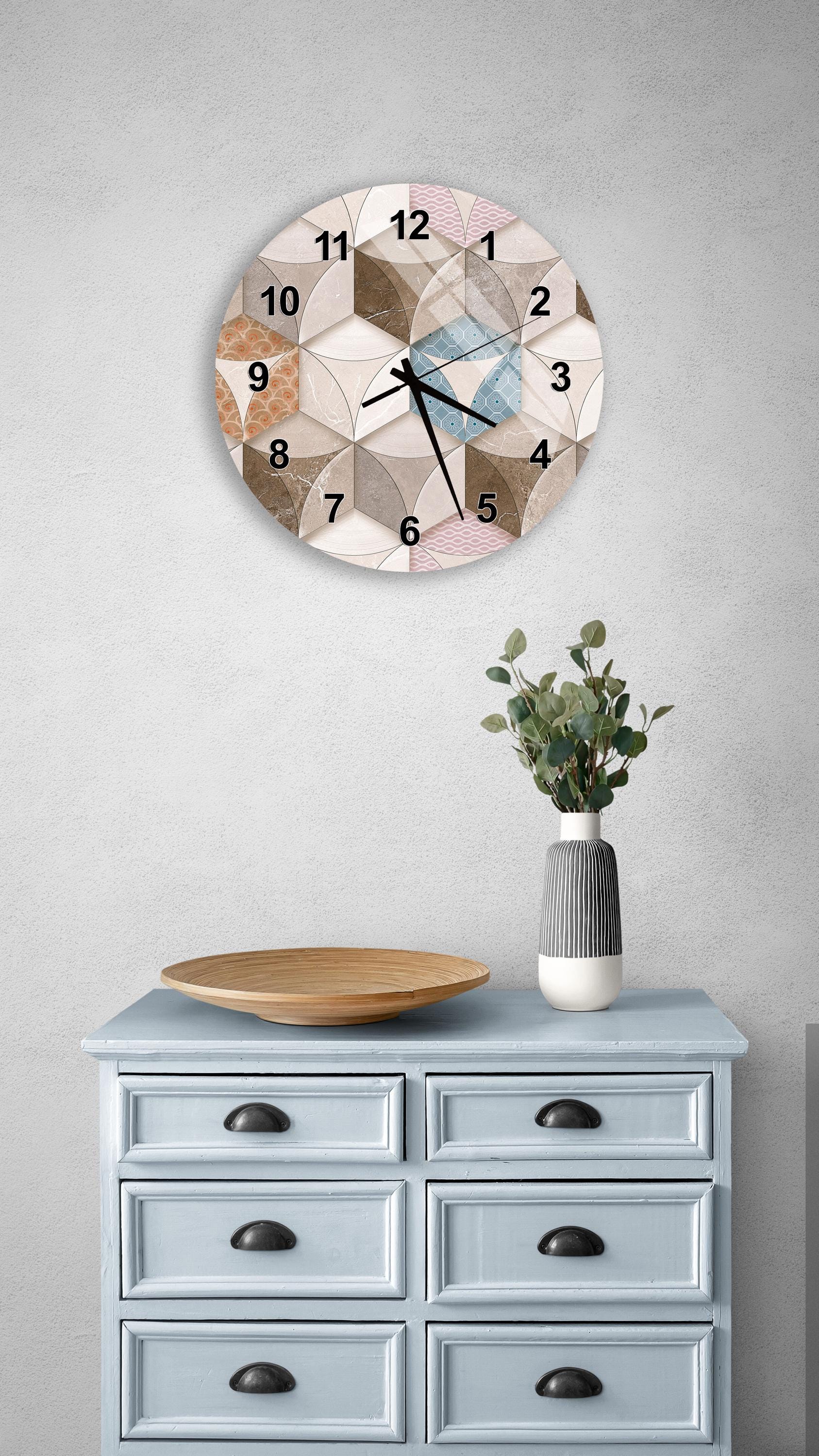 a wall clock with a geometric pattern, a wooden bowl, and a vase with greenery on a light blue dresser.