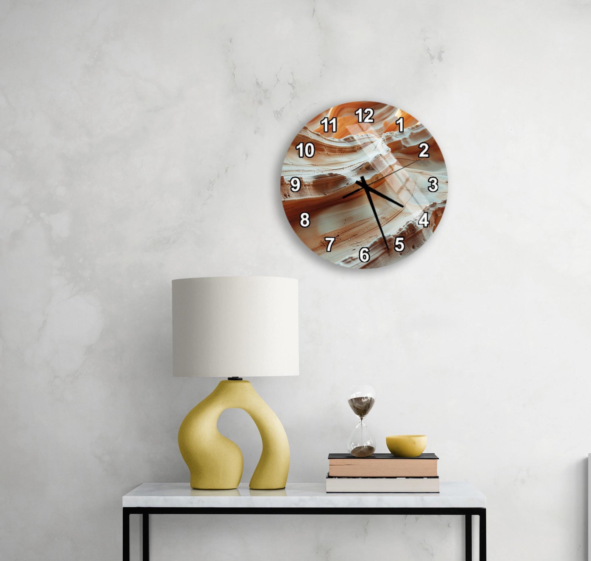 a modern wall clock with a unique design, a yellow lamp on a white table, and a stack of books and a glass of wine on the table.