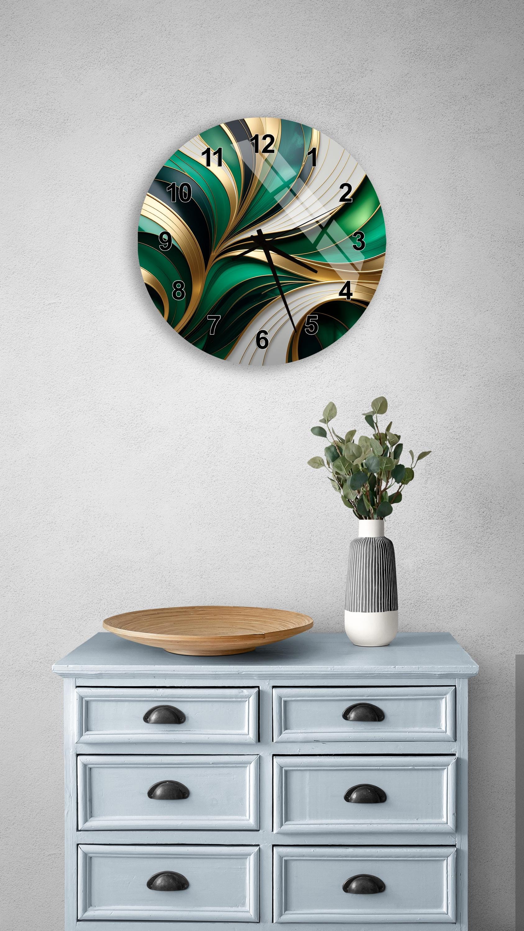 a wall clock with a green and gold design, mounted on a wall above a light blue dresser with six drawers. The dresser also has a vase with greenery on it, and a wooden plate on top.