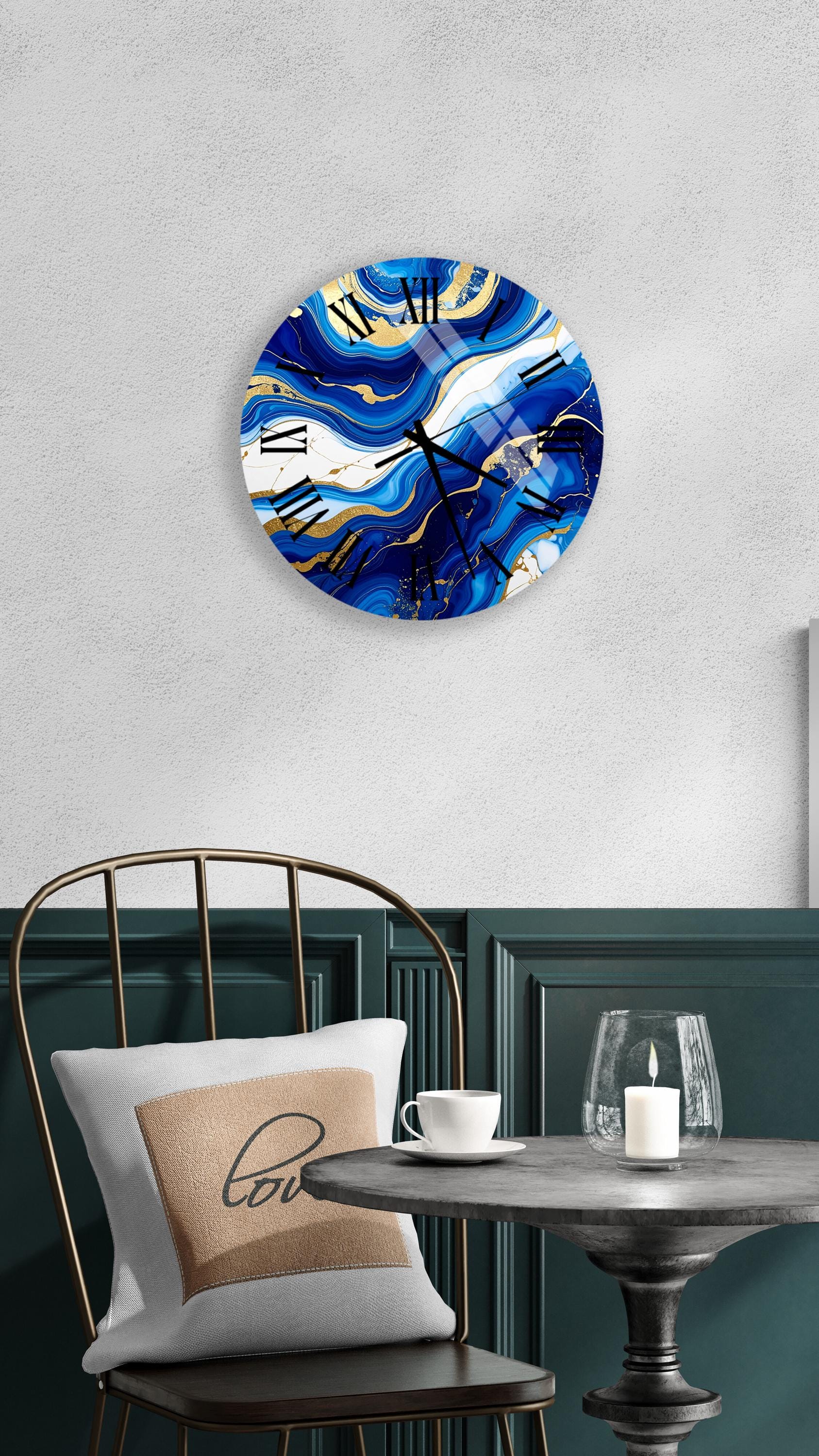 a modern and stylish interior design with a round wall clock featuring a blue and gold marble pattern, a white table with a candle and a cup, and a black metal chair with a white pillow.