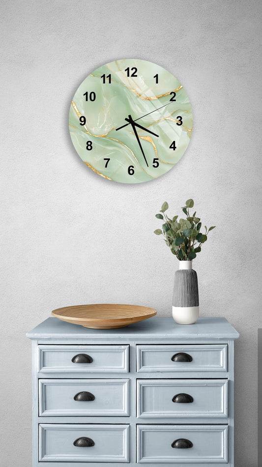 a wall clock with a marble-like green and gold design, mounted on a wall above a light blue wooden dresser with six drawers. The dresser also has a vase with greenery on it, and a wooden plate on top.