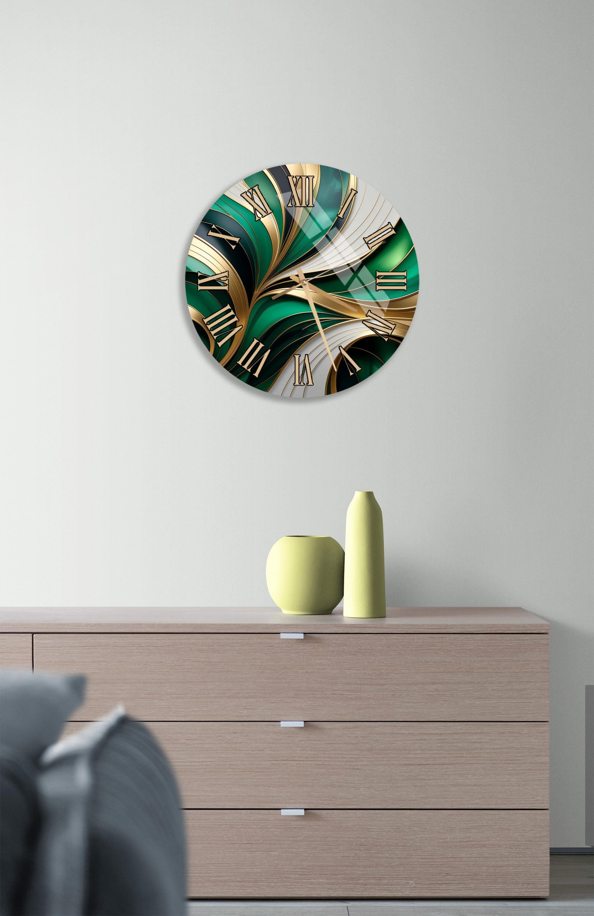 a modern clock with a green and gold design, mounted on a wall above a wooden dresser.