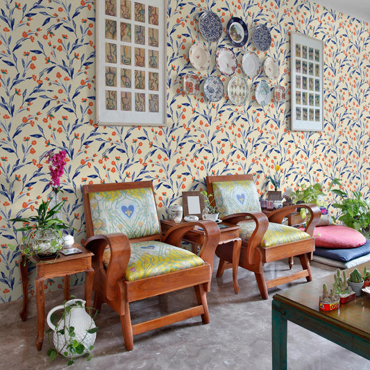 a cozy living room with a floral wallpaper, two wooden armchairs, and a wooden side table. Above the armchairs, there are several plates and wall hangings, creating a visually appealing and eclectic decor.