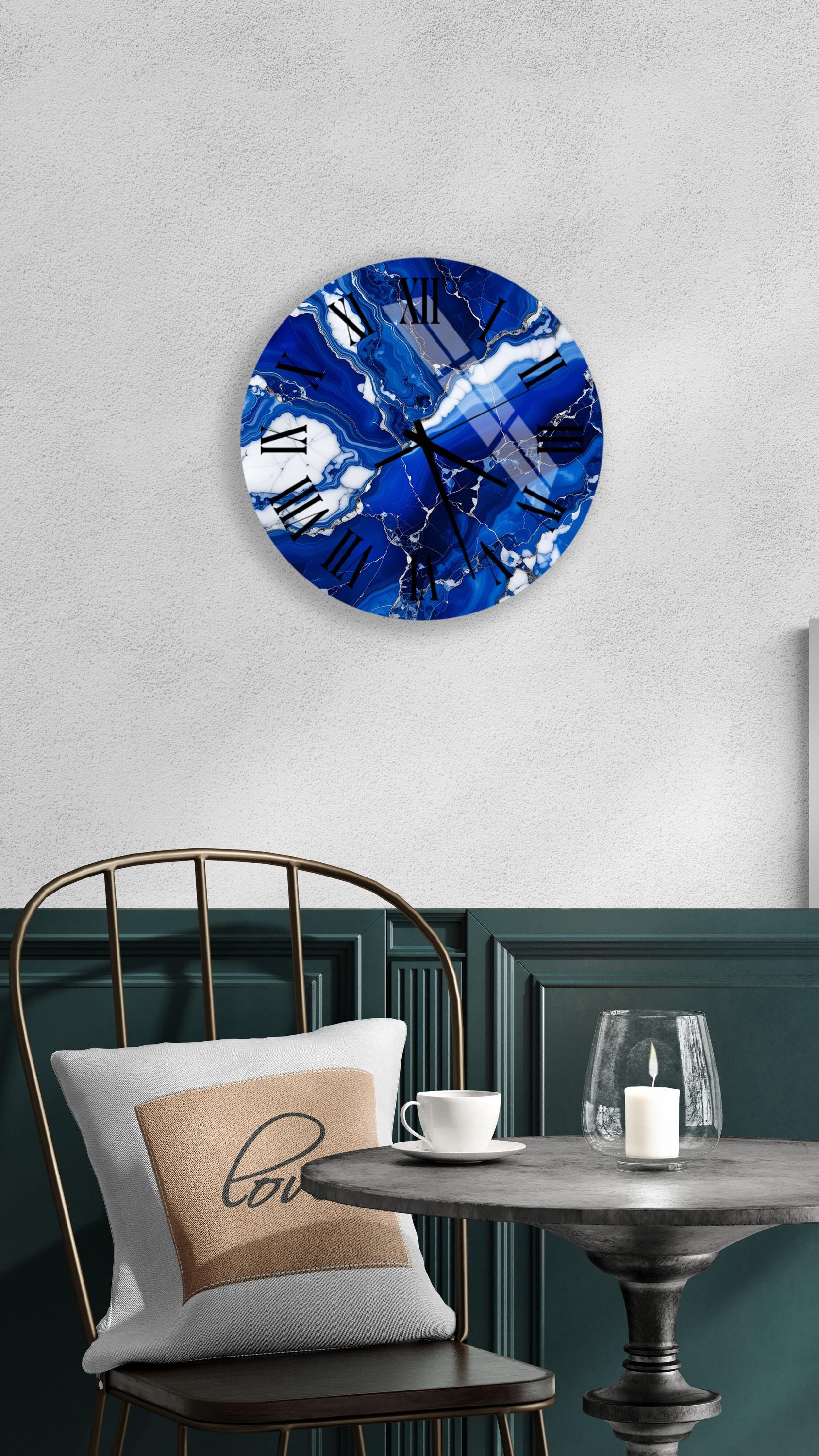a modern interior design with a round wall clock featuring a blue marble-like pattern, a white table with a candle, and a black metal chair.